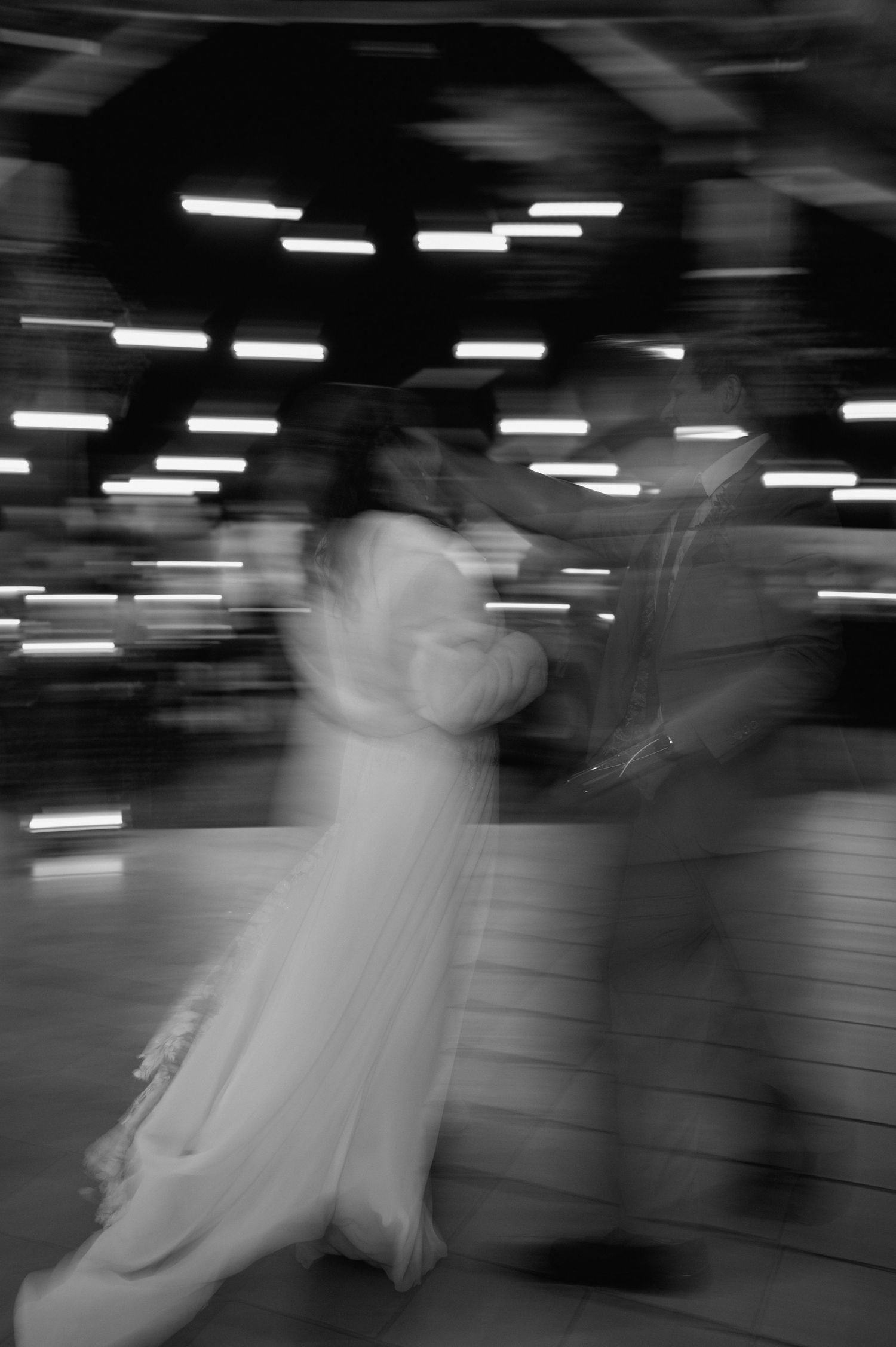 A black and white motion blur photo of dancers spinning at a wedding reception.