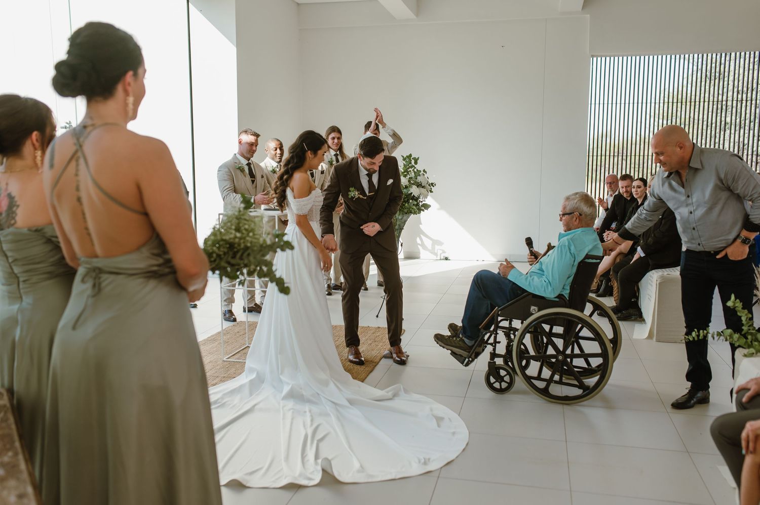 Wedding ceremony in bright modern space with guests and wheelchair-accessible seating.