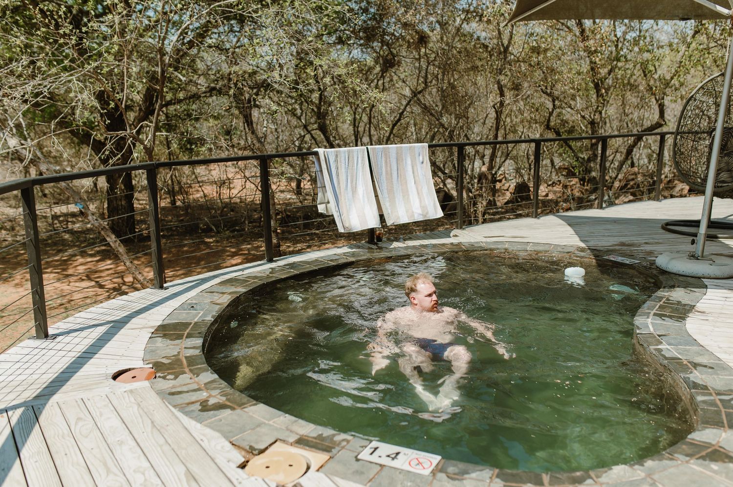 People swimming and relaxing in a natural rock pool with clear turquoise water.