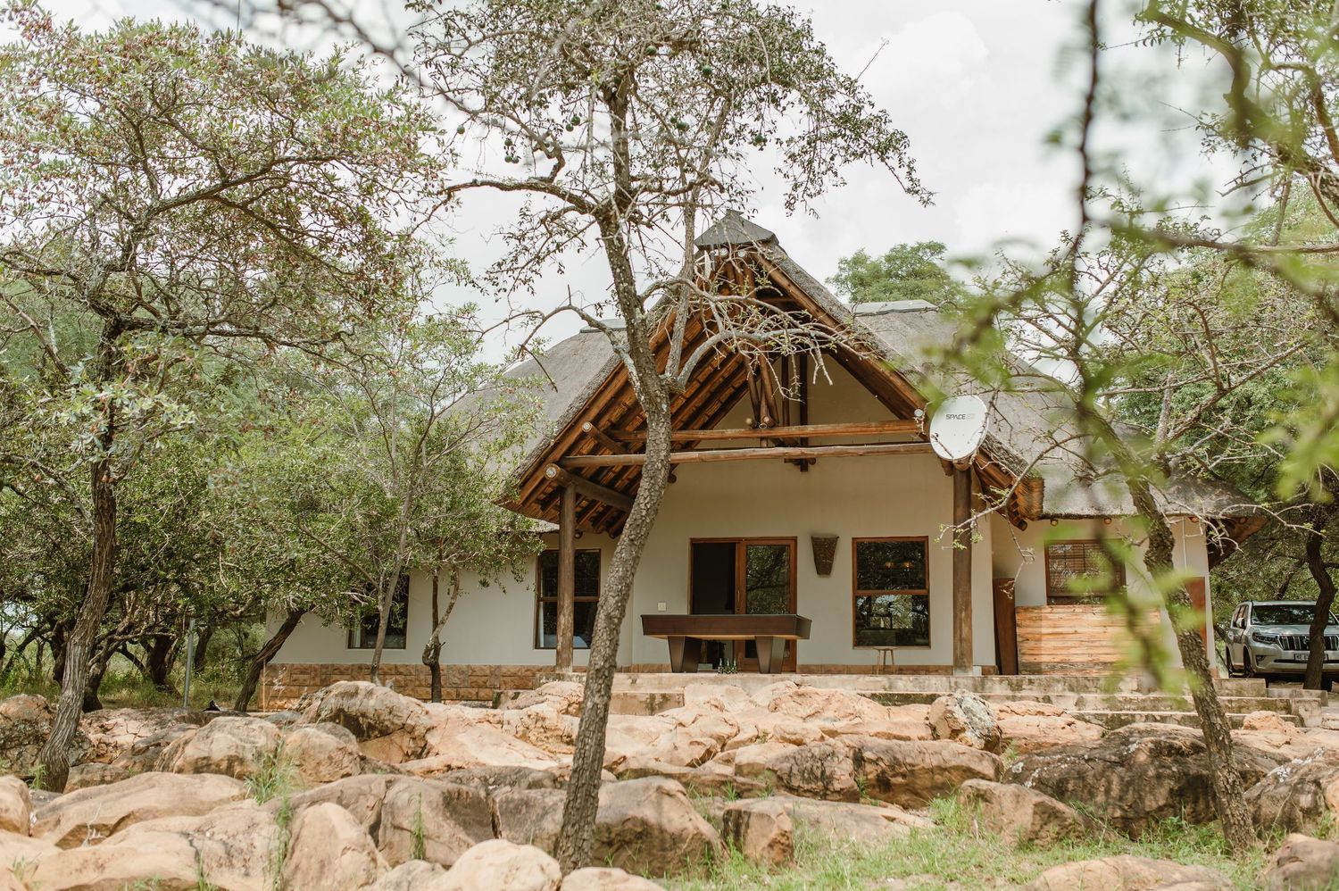 Panoramic view of rustic safari lodges nestled among trees in a natural wilderness setting.