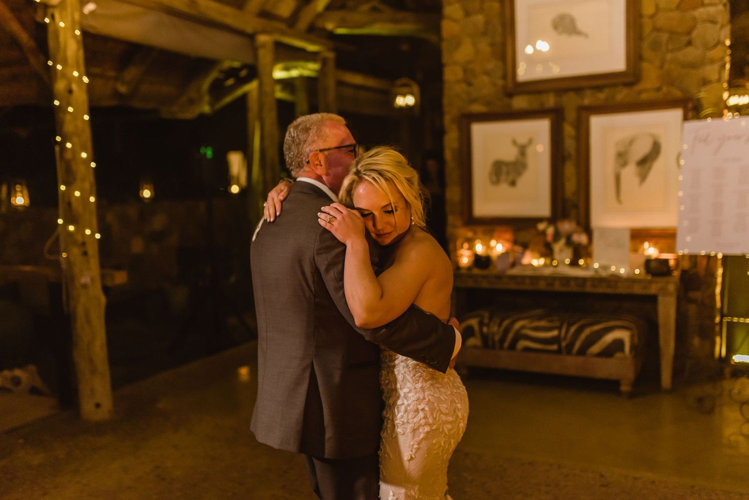Couples dancing in a warmly lit rustic barn venue with string lights overhead.