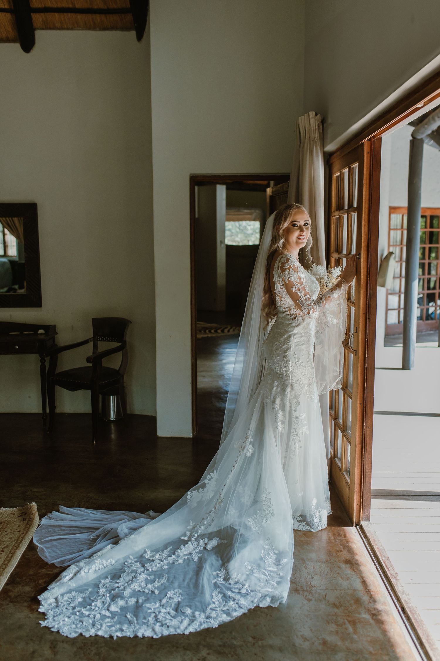 Dramatic full-length shots of wedding dress with flowing train against rustic interior windows.