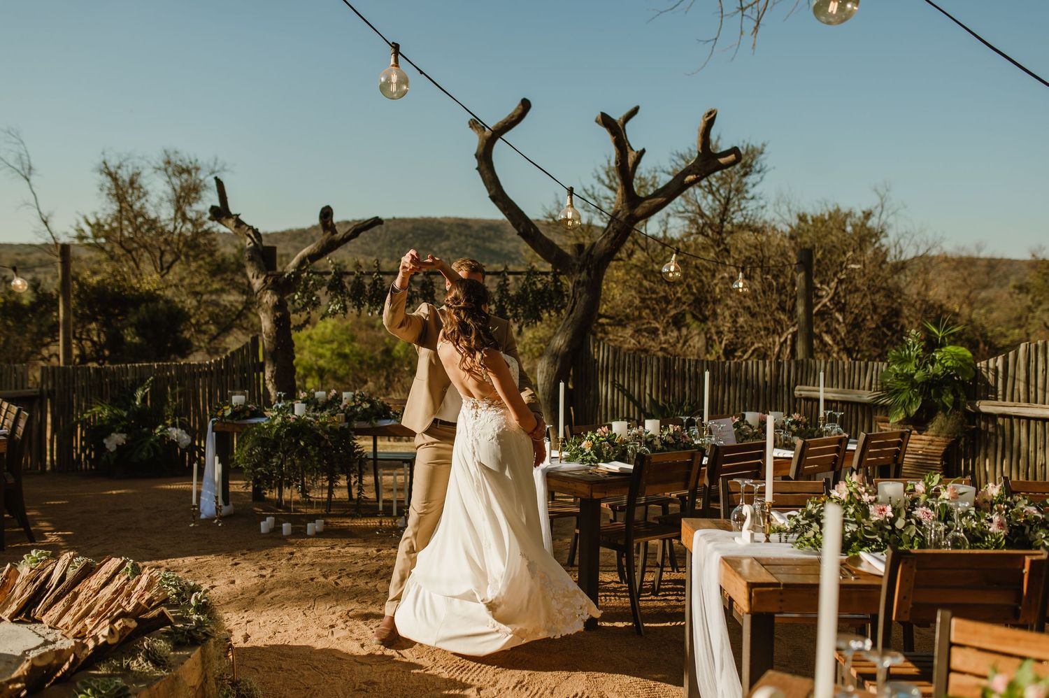 Elegant outdoor wedding venue with string lights and desert mountain backdrop.