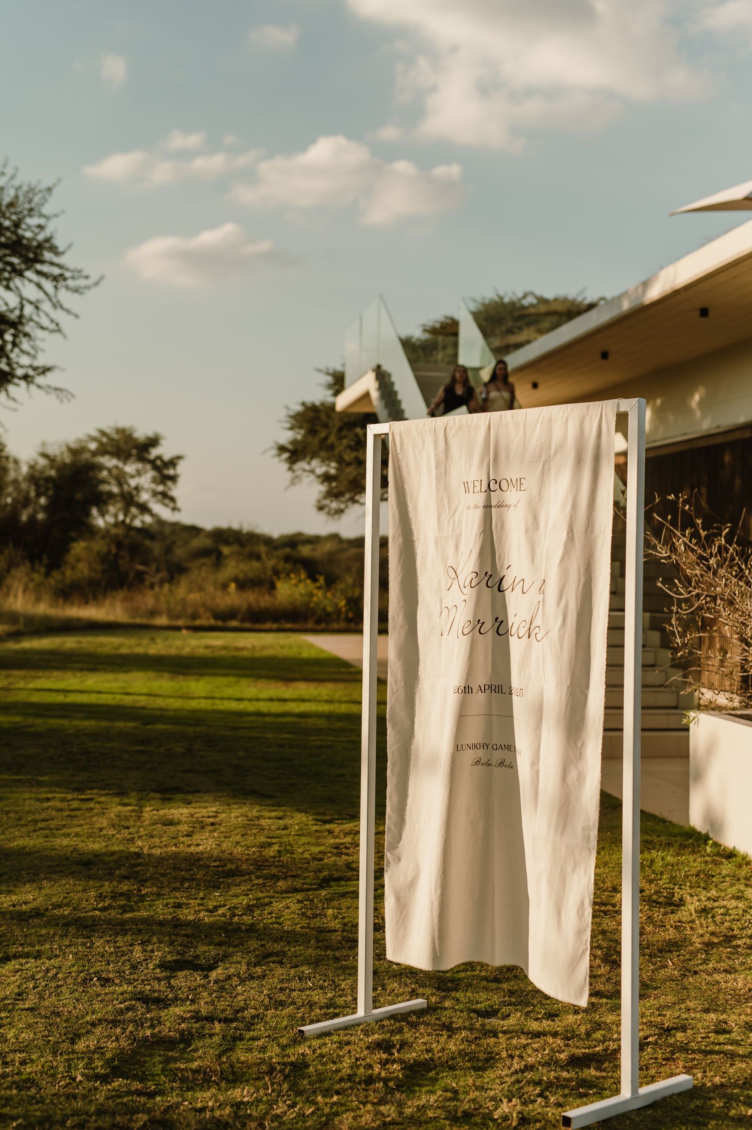 White wedding signs displayed on outdoor stands against natural landscape.