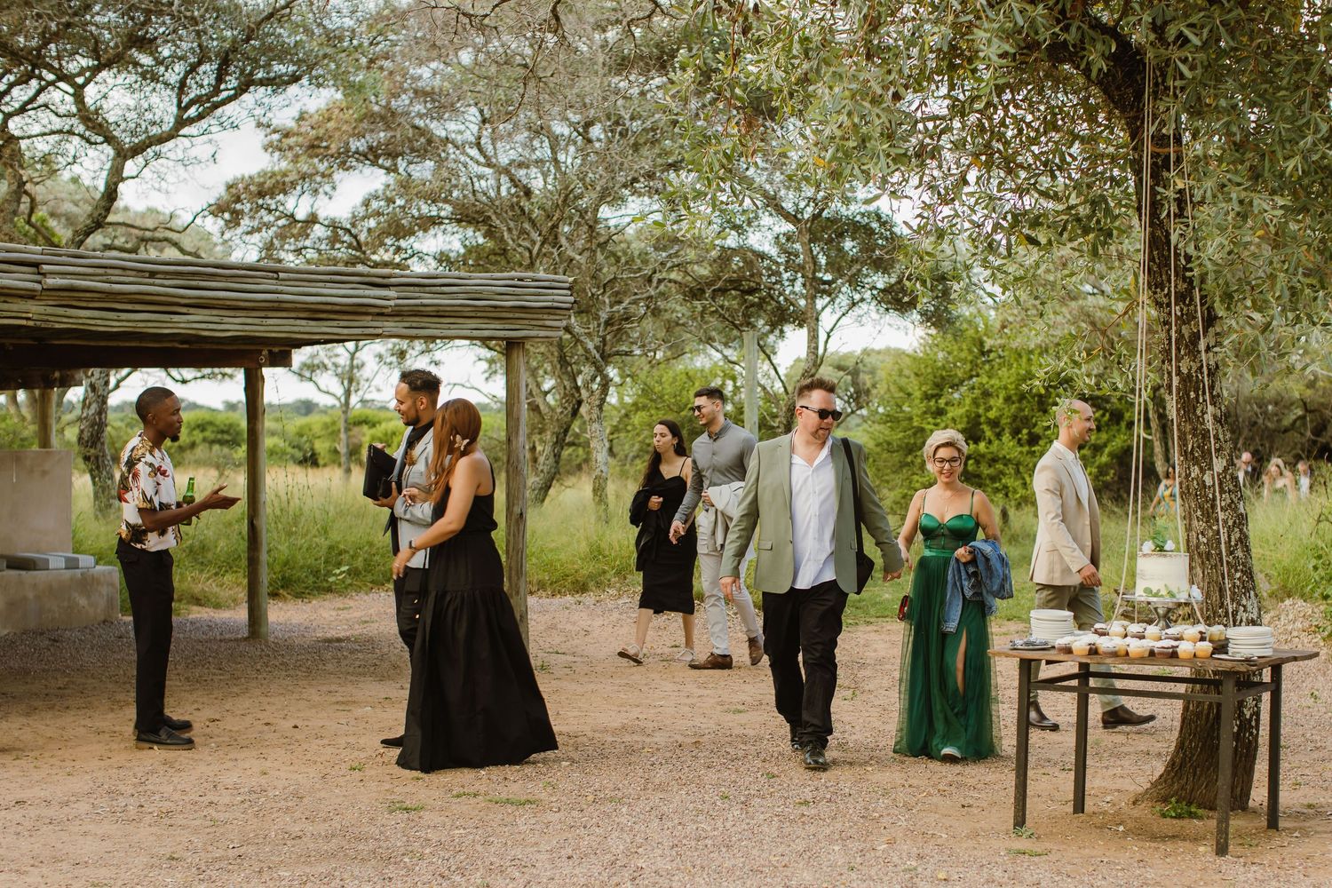 Wedding party walking together through a scenic outdoor venue with trees and natural surroundings.