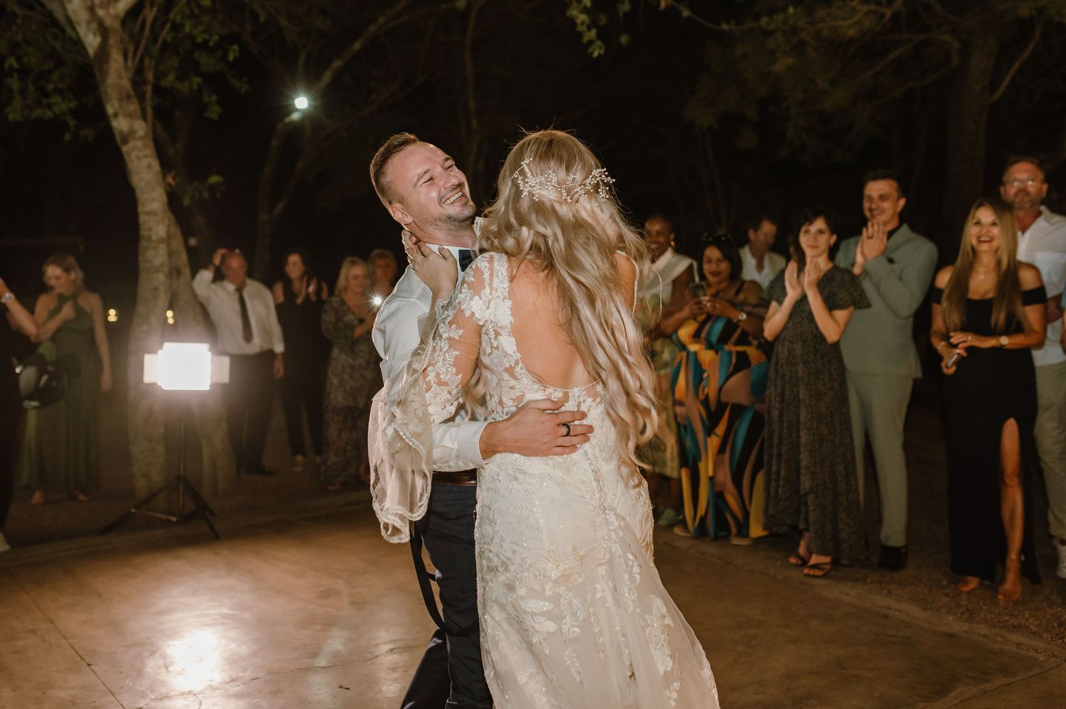 A romantic dance moment captured at a nighttime outdoor wedding reception.