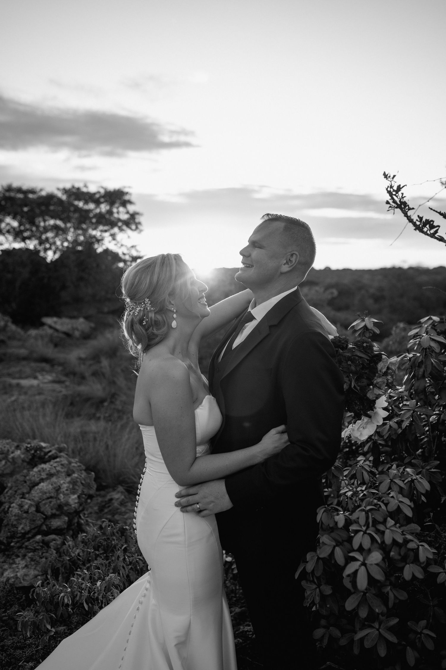 Black and white wedding portrait capturing an intimate moment between newlyweds at sunset.