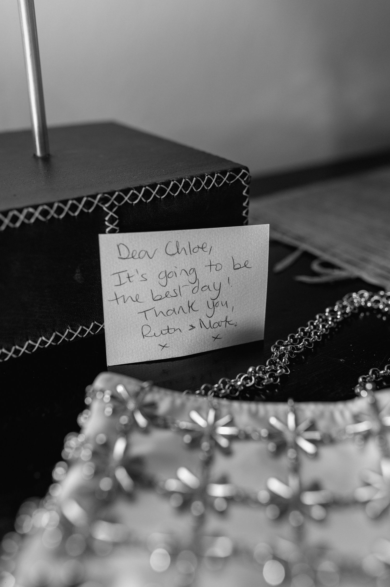 Black and white close-up of handwritten note with bokeh effect in foreground.