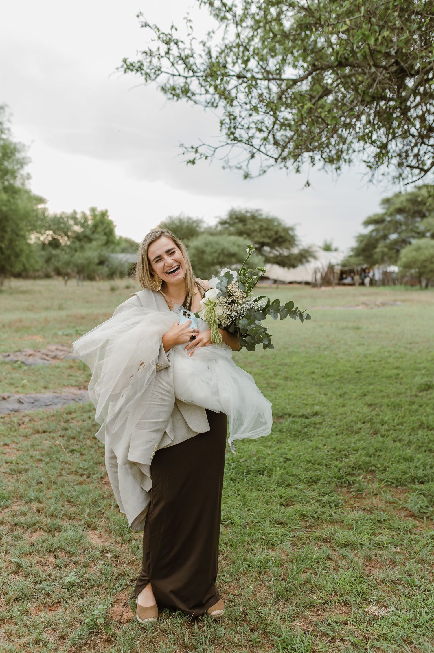 A playful wedding photoshoot in a grassy field with flowing white dress and natural movements.