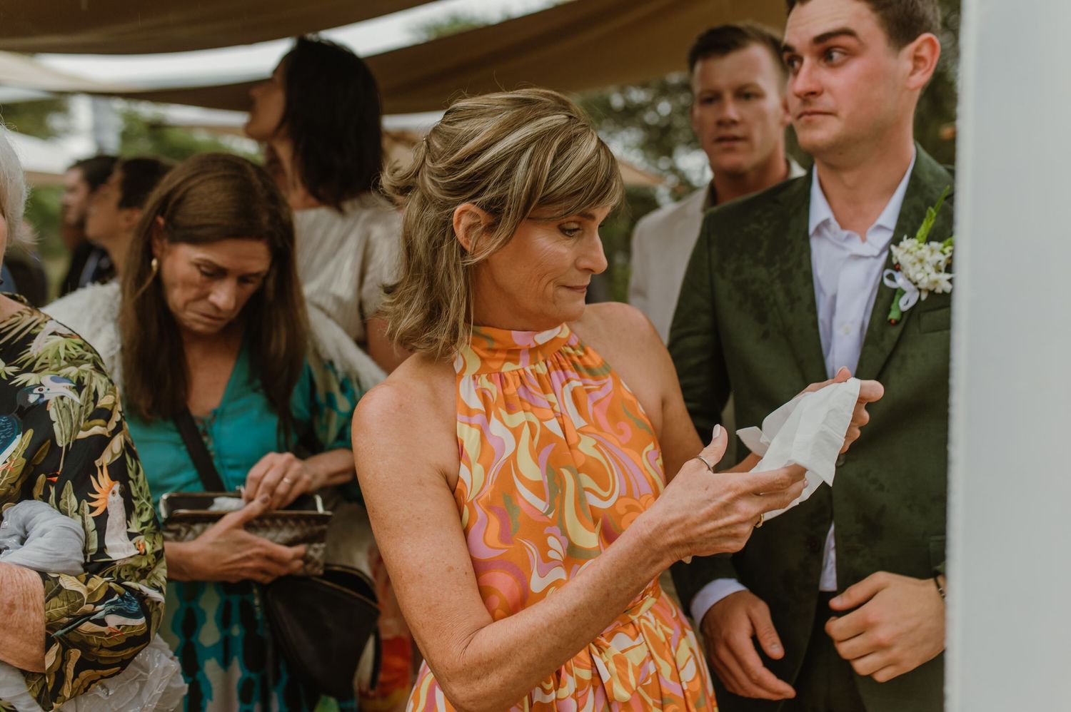 Wedding reception guests mingle under white tent canopies outdoors.