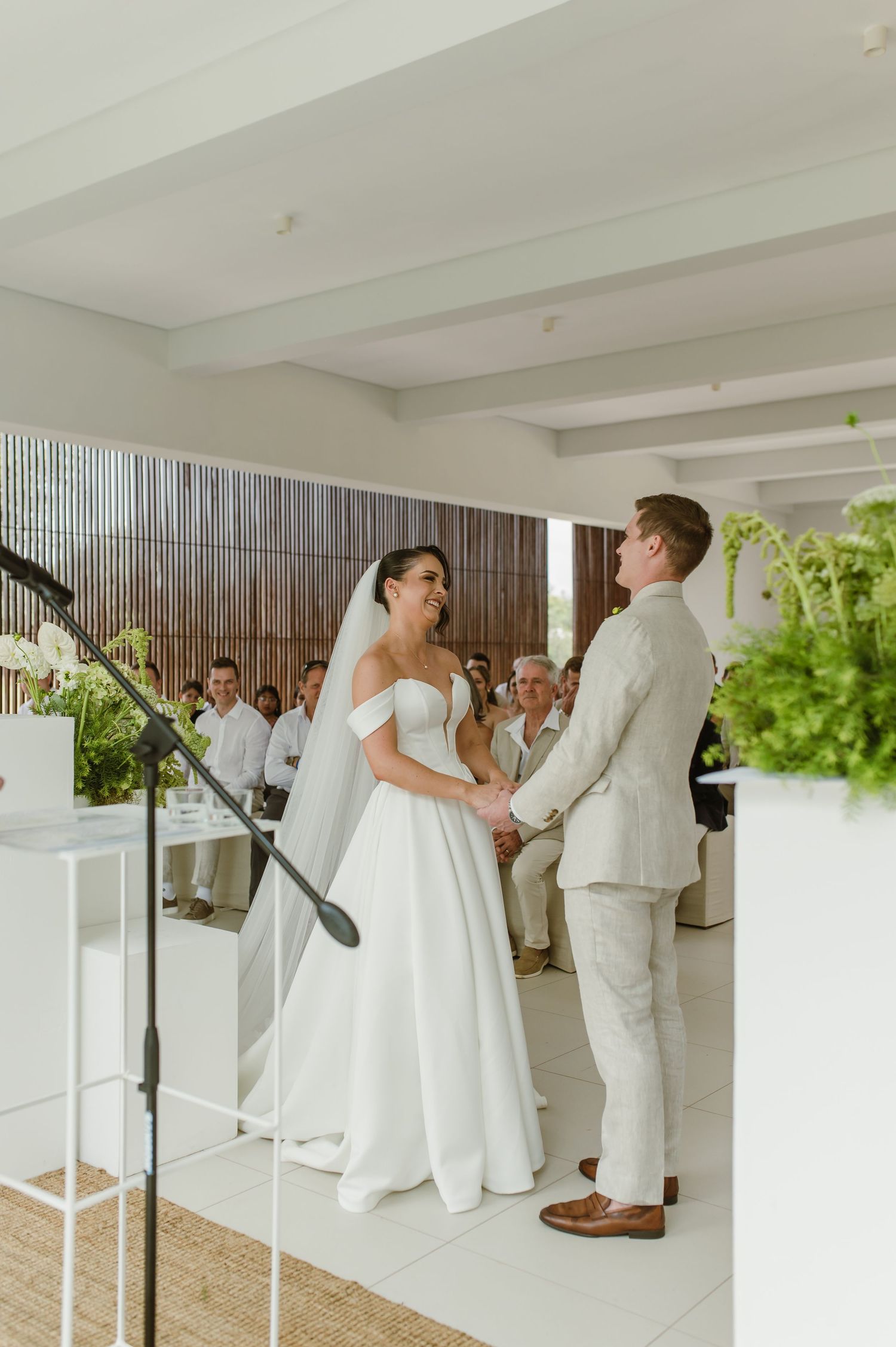 Modern indoor wedding ceremony with couple exchanging vows in front of seated guests.