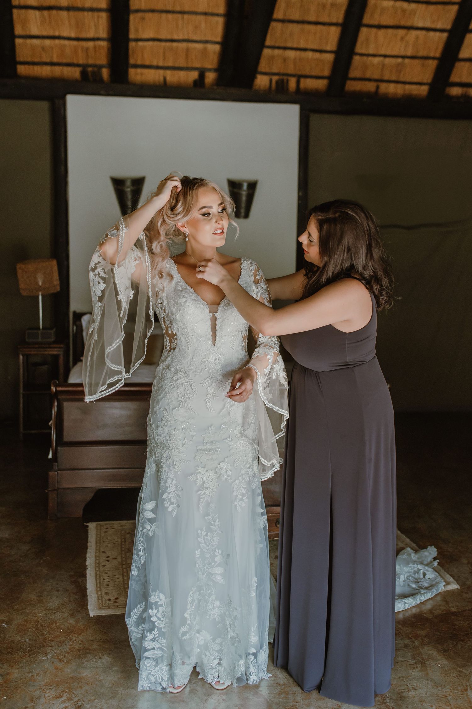 Wedding dress fitting moment captured in warm natural lighting with rustic decor.
