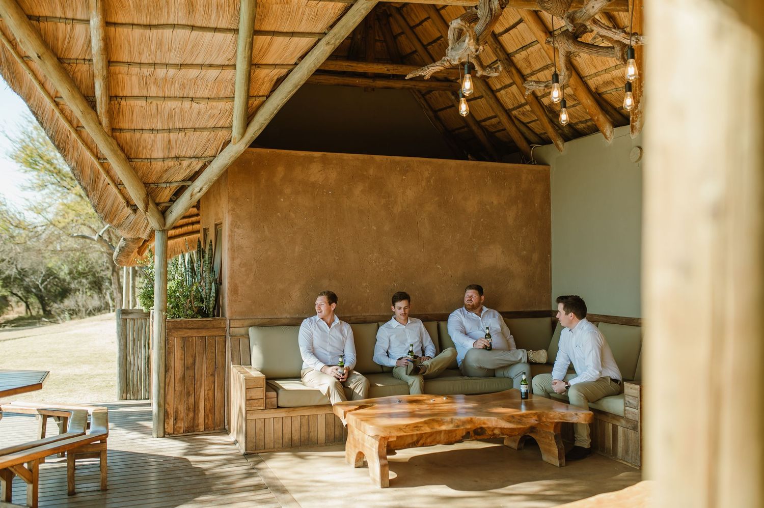 Group relaxing in covered outdoor lounge area with rustic wooden beams.