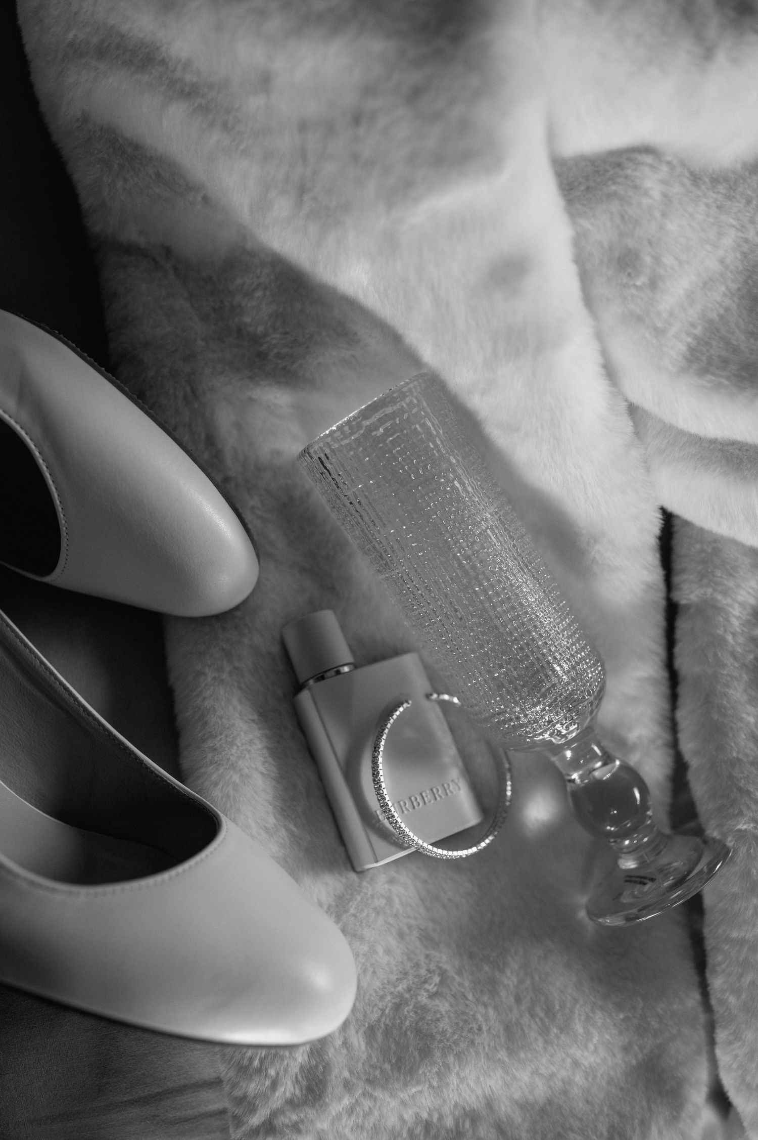 A black and white close-up of elegant bridal shoes on a textured surface.