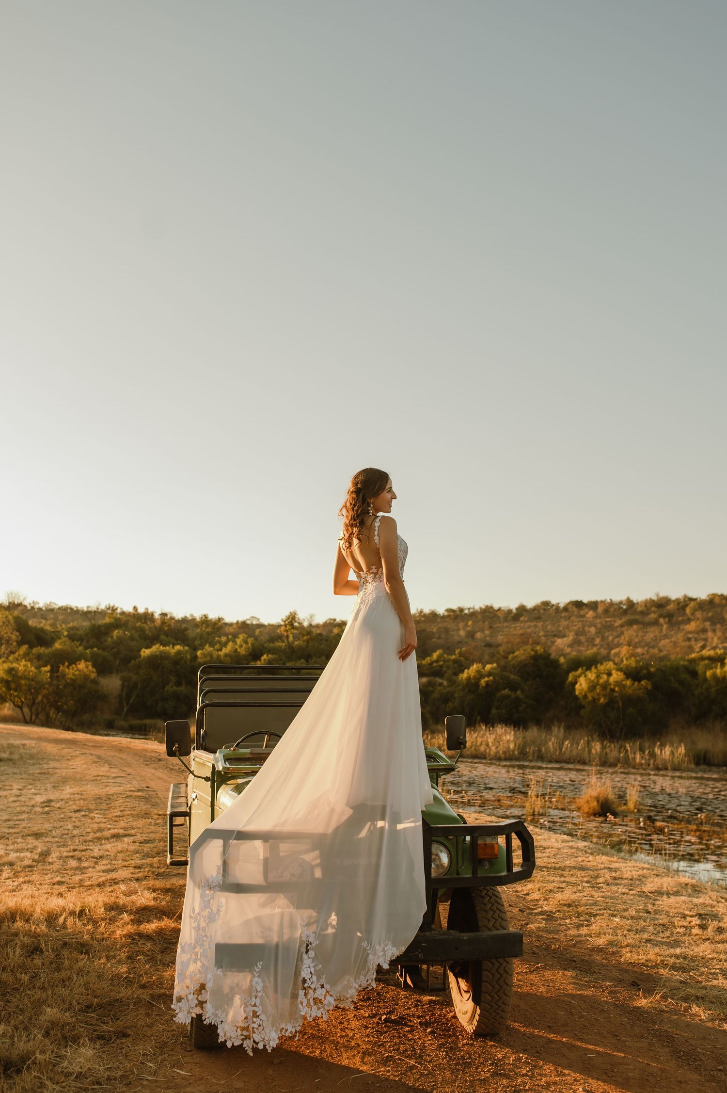 Wedding couple poses with vintage truck against sunset landscape.