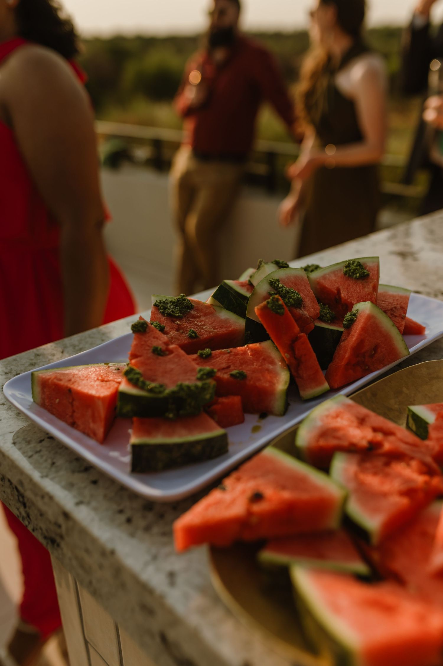 Fresh watermelon slices garnished with mint leaves displayed on silver serving tray.