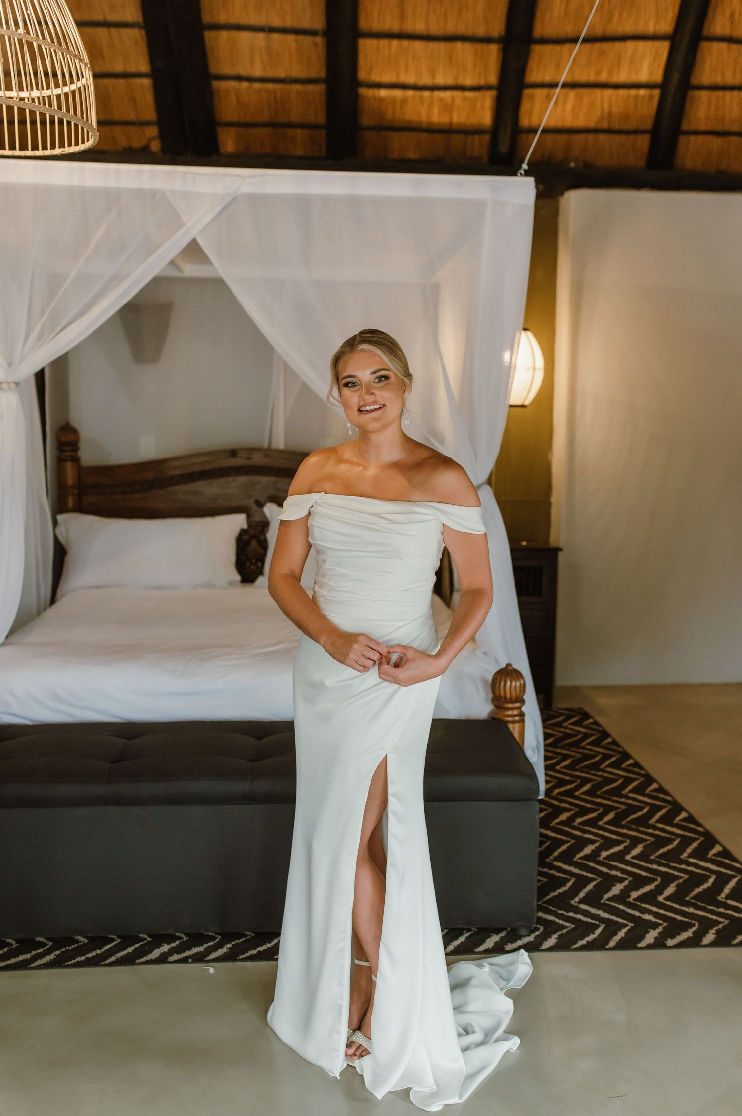 Full-length view of white wedding dress against geometric patterned rug in tropical setting.
