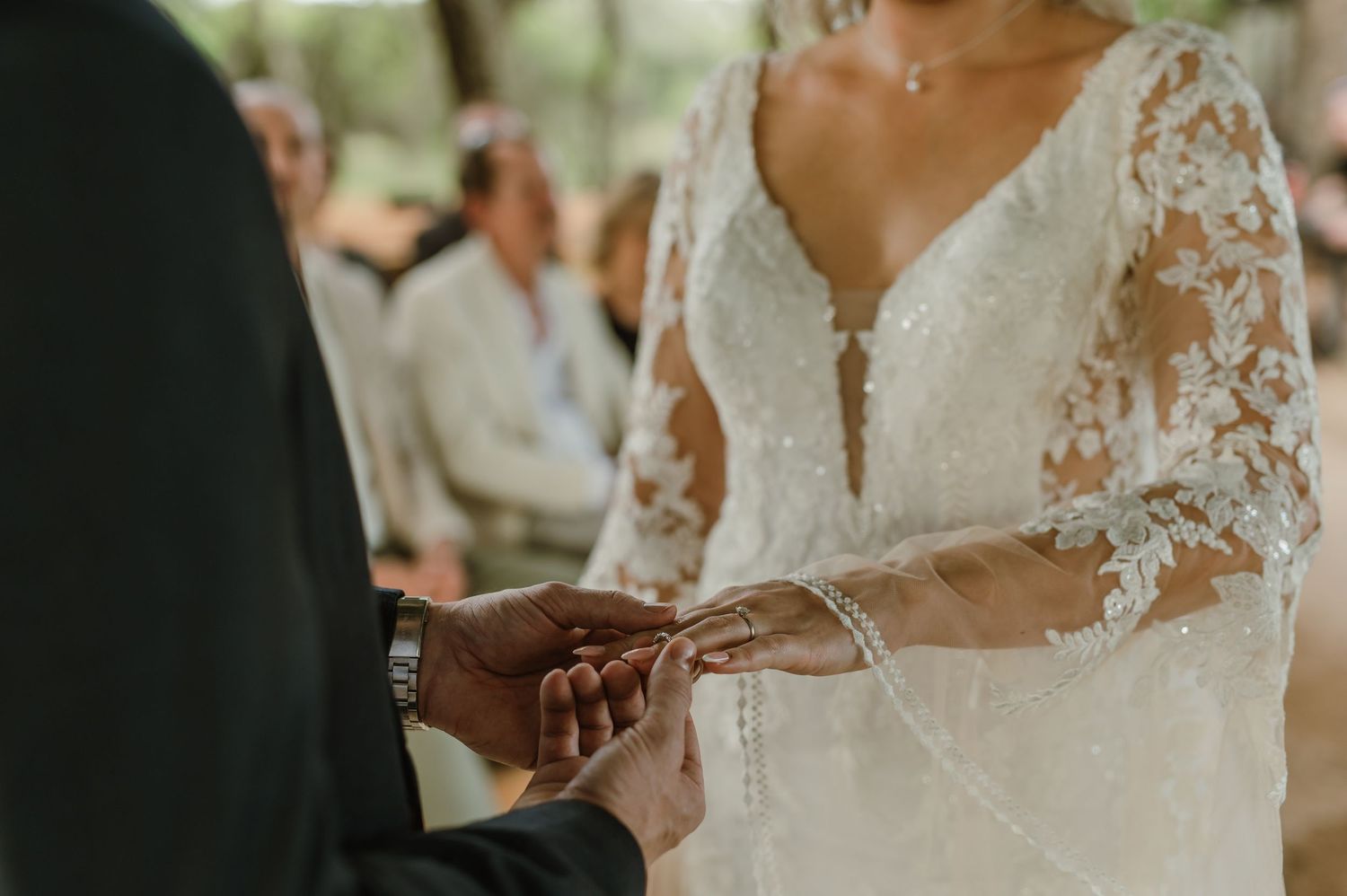 Close-up shot of exchanging wedding rings during an outdoor ceremony.