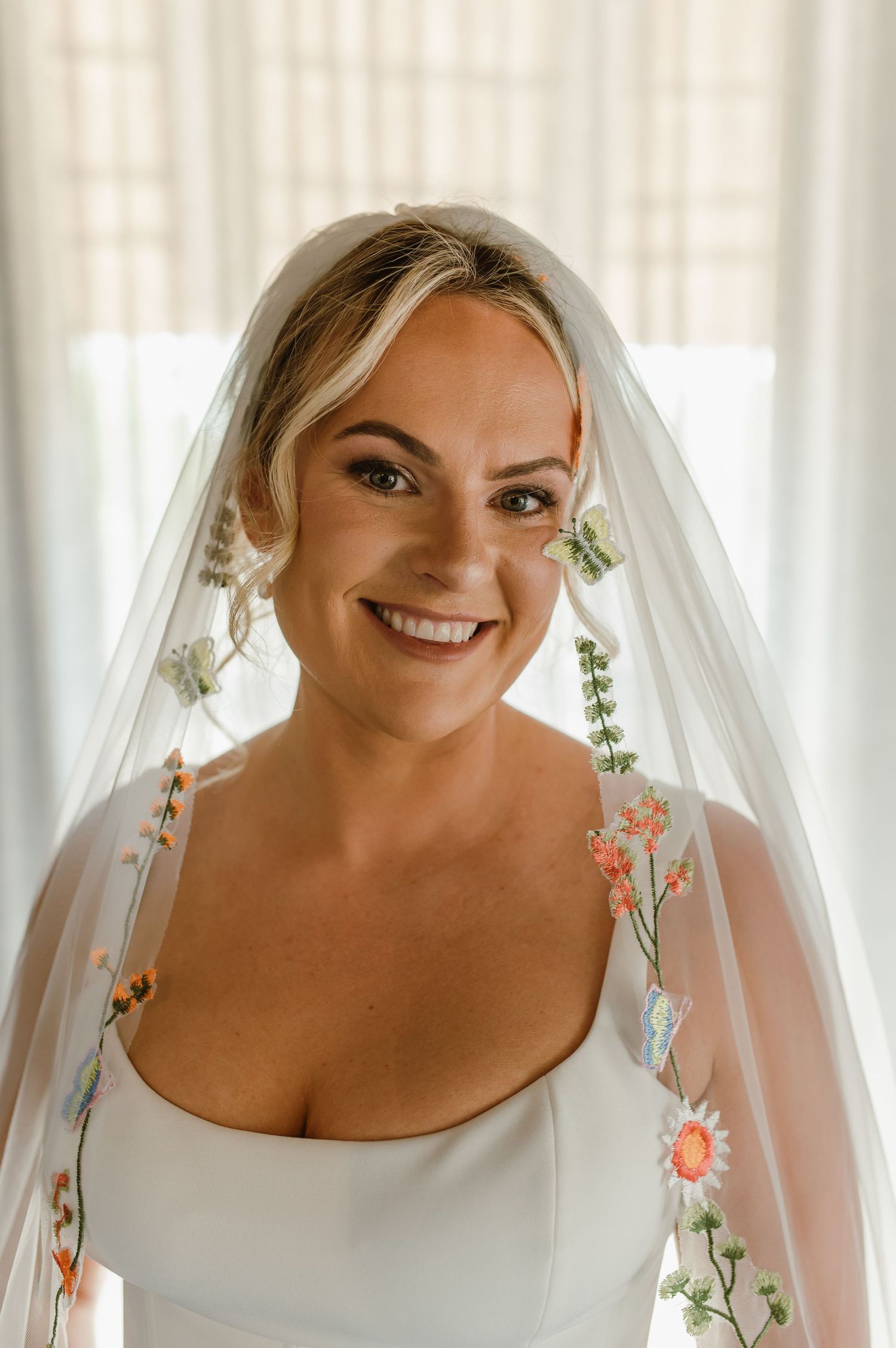 Close-up details of delicate floral embroidered wedding veil against white background.
