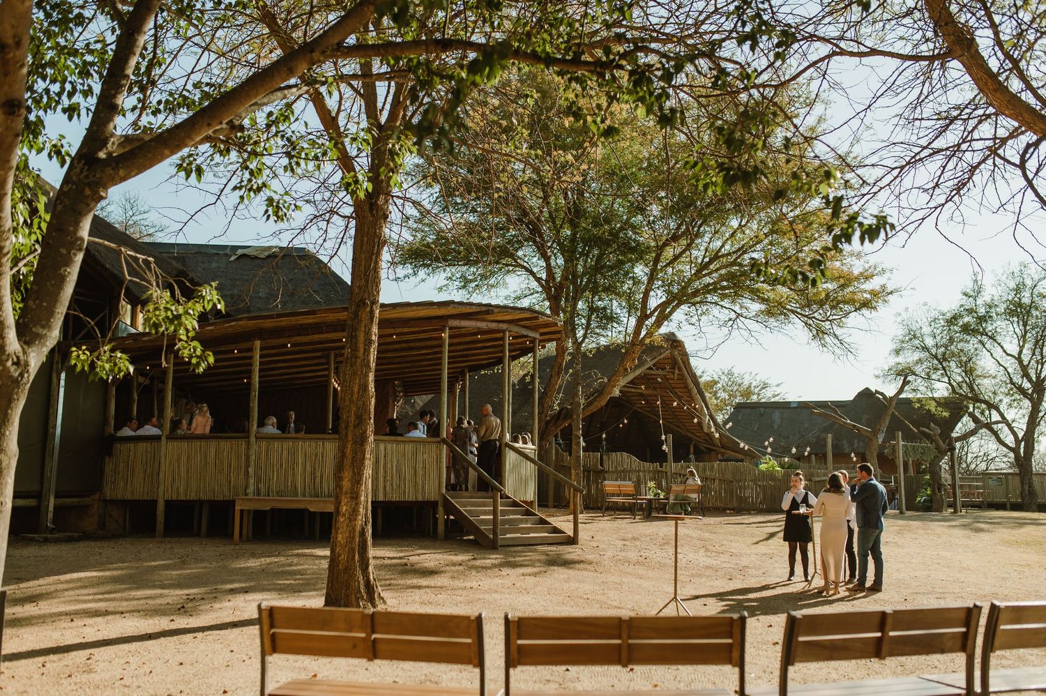 Panoramic view of rustic outdoor wedding venue surrounded by trees and natural landscape.