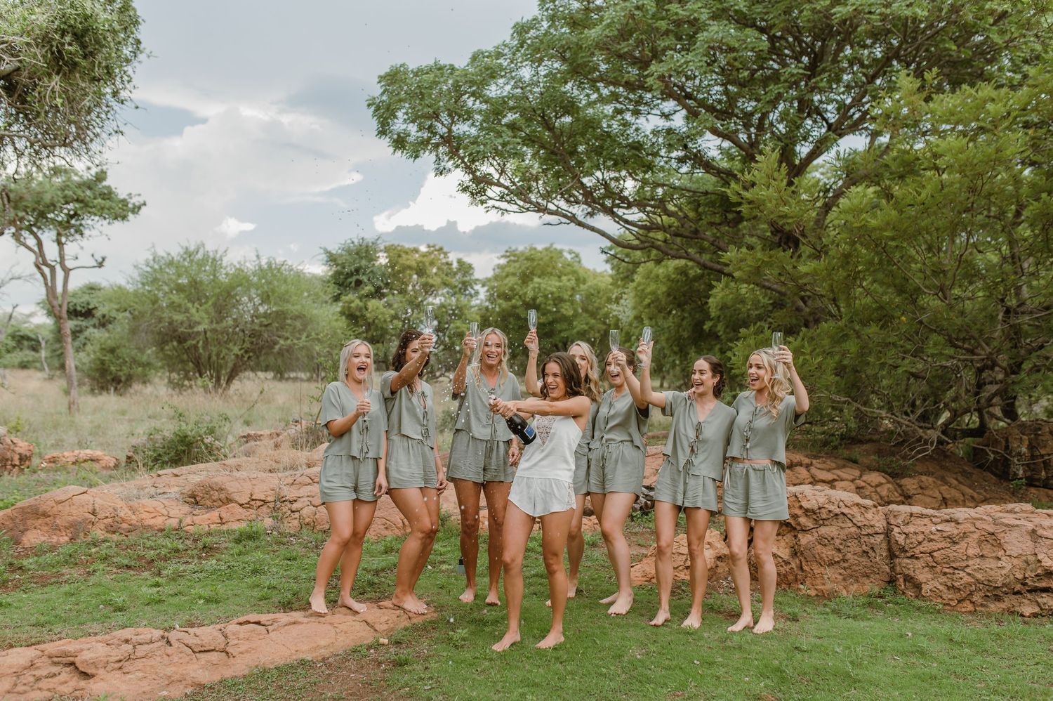 Bridal party in matching outfits posing outdoors on natural terrain.