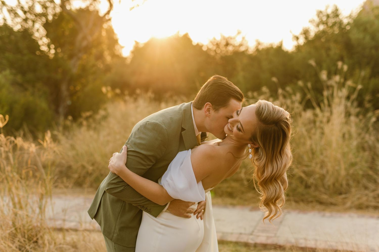 Two people share an intimate moment while dancing outdoors during a golden sunset.