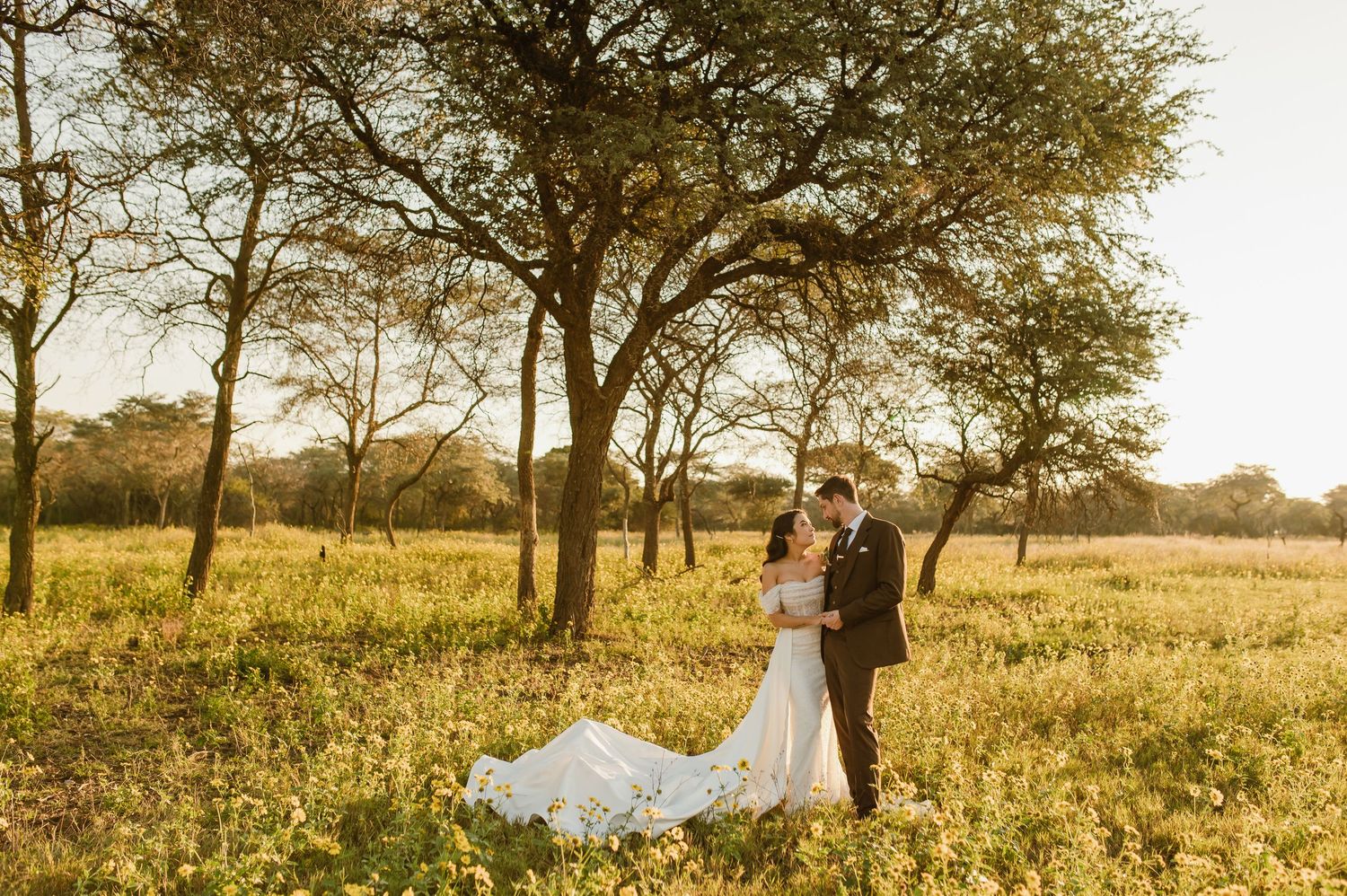 A wedding portrait in a serene African savanna setting during golden hour.
