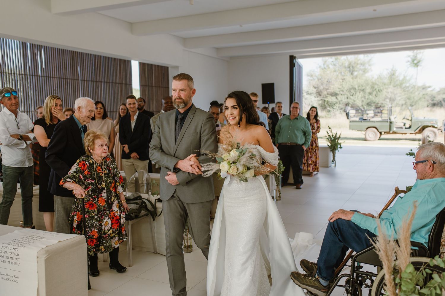 Wedding ceremony in progress inside bright modern venue with guests seated in rows.