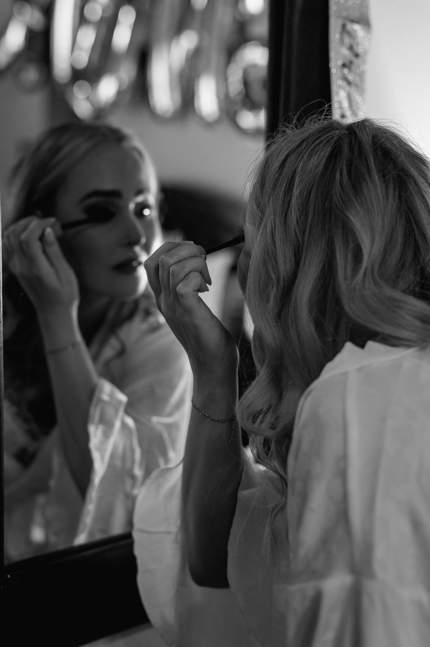 Black and white photo showing preparation moments with hair styling and makeup application.