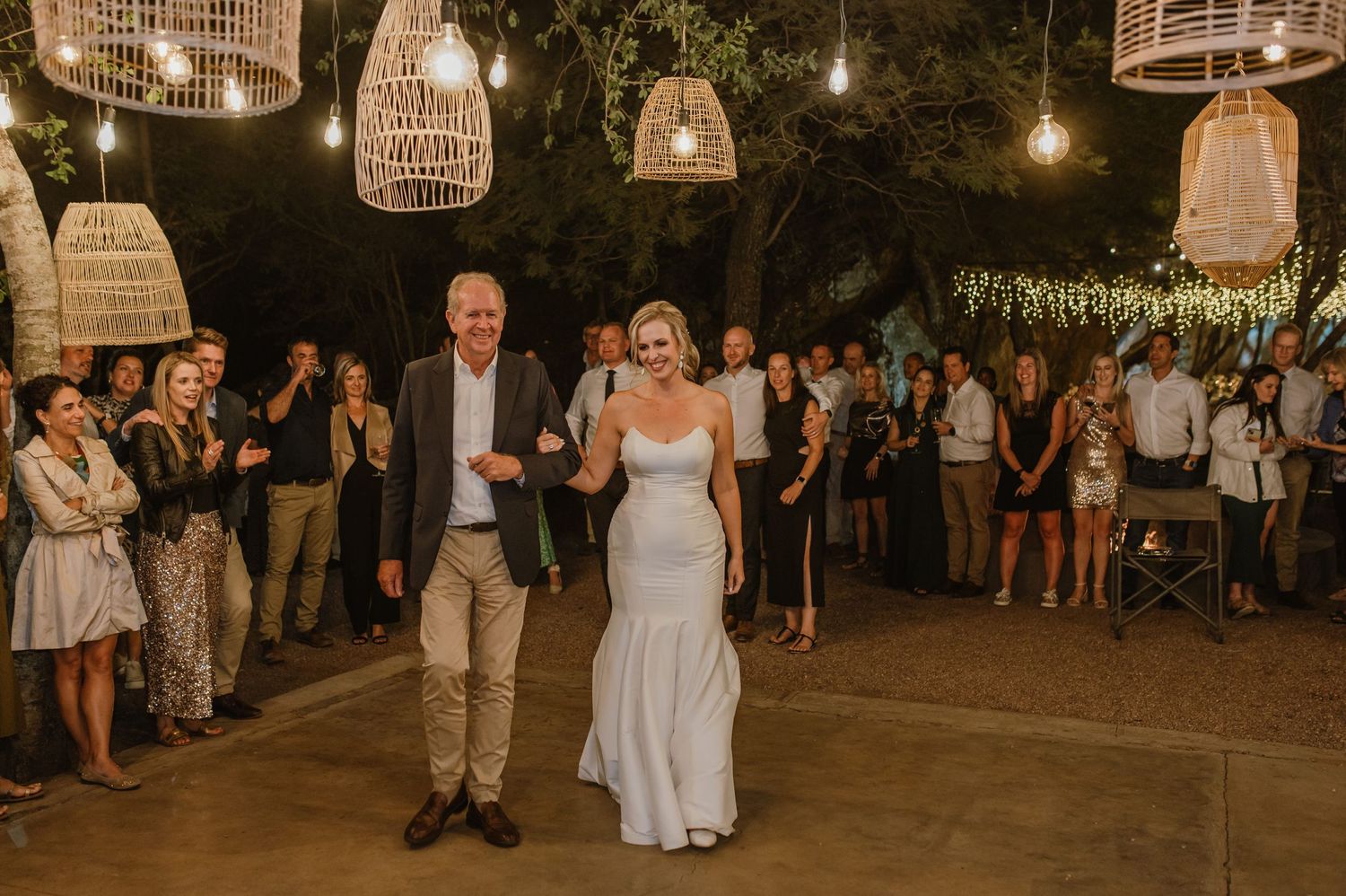 Evening outdoor wedding dance floor with hanging lanterns and ambient lighting.