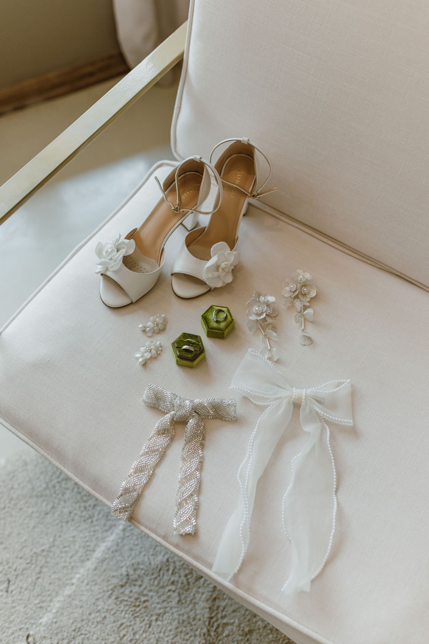 Wedding accessories including white shoes, floral hairpieces, and ribbons arranged on a light surface.