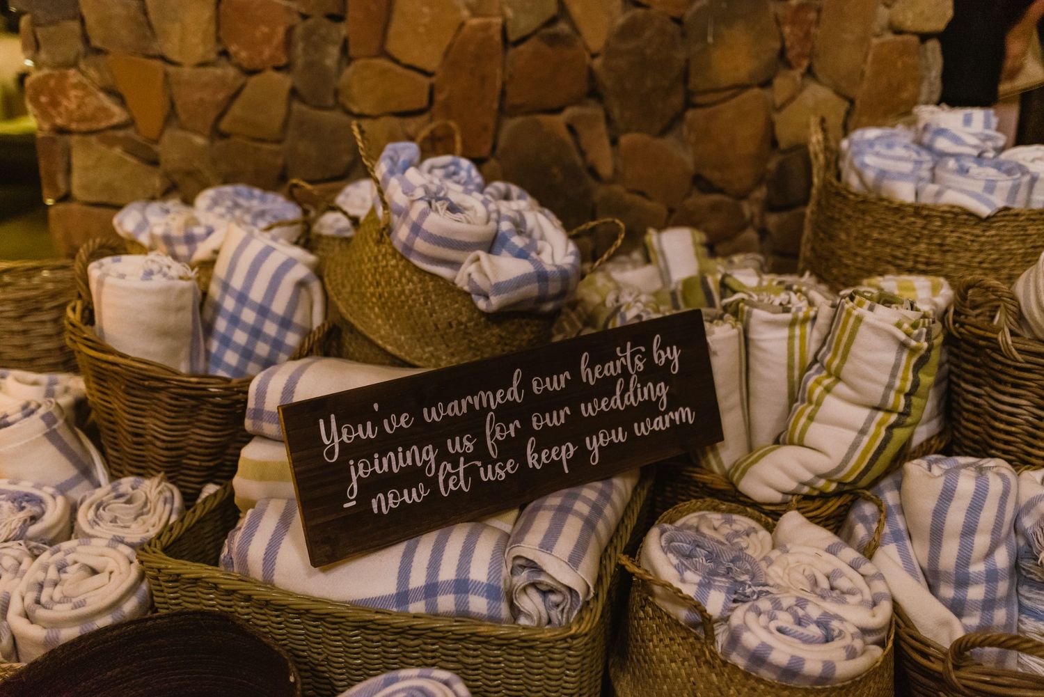 Rustic wedding favors arranged in woven baskets with blue and white checkered fabric.