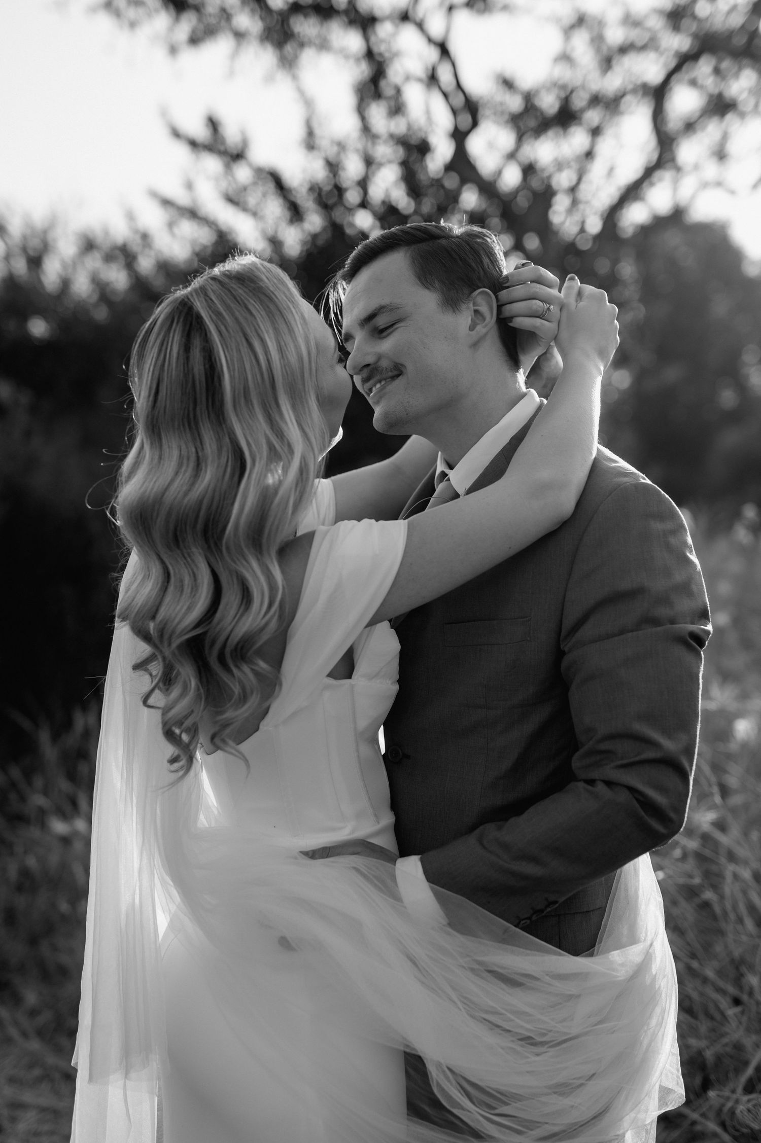Black and white wedding portrait showing an intimate embrace during golden hour.
