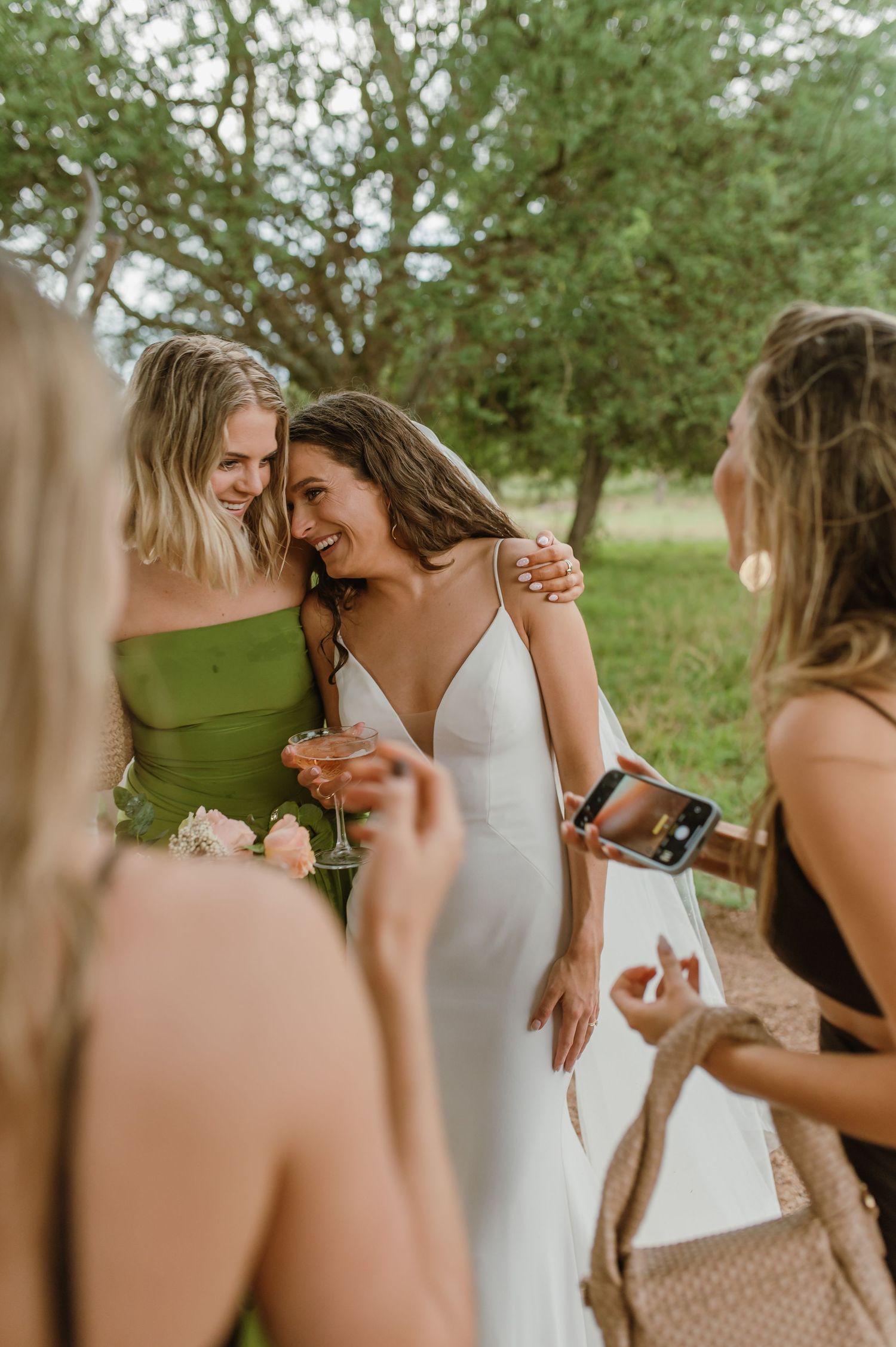 Wedding party members share joyful moments during outdoor celebration.