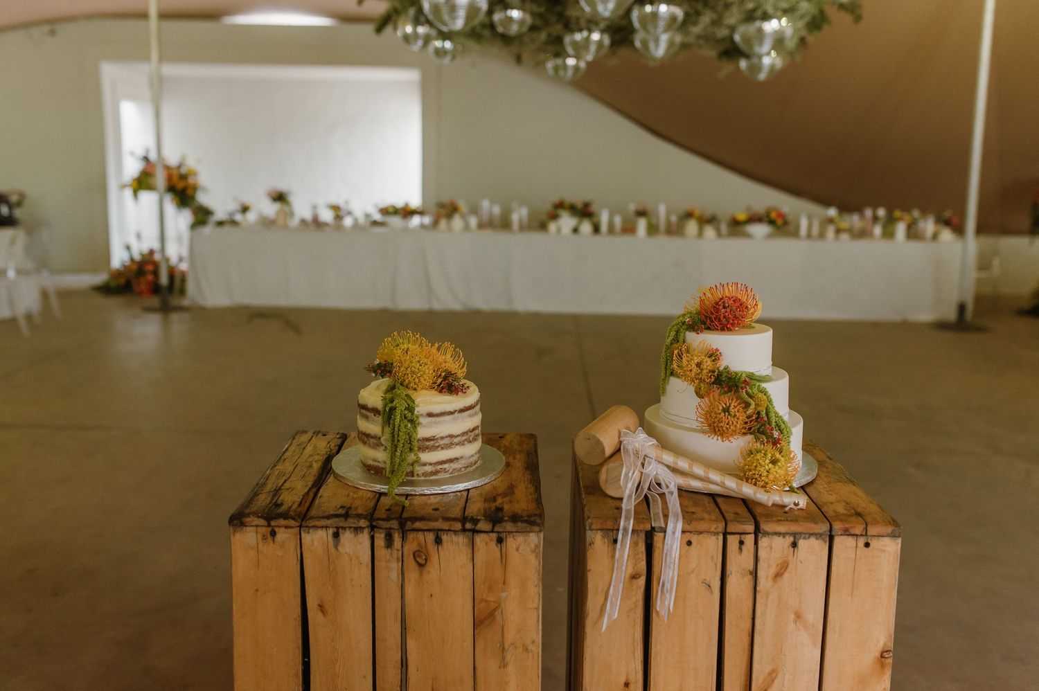 Wedding cakes displayed on wooden crates at an outdoor reception.