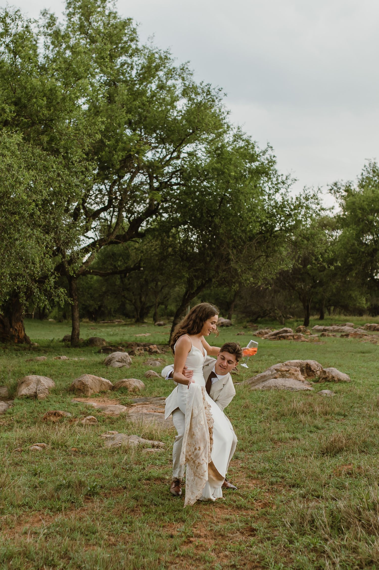 Artistic wedding photography in a natural field with scattered rocks and trees.