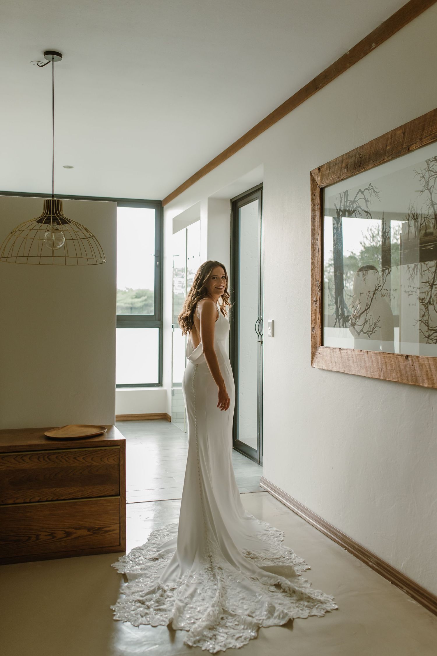 A flowing white wedding gown with train photographed in a modern interior setting.