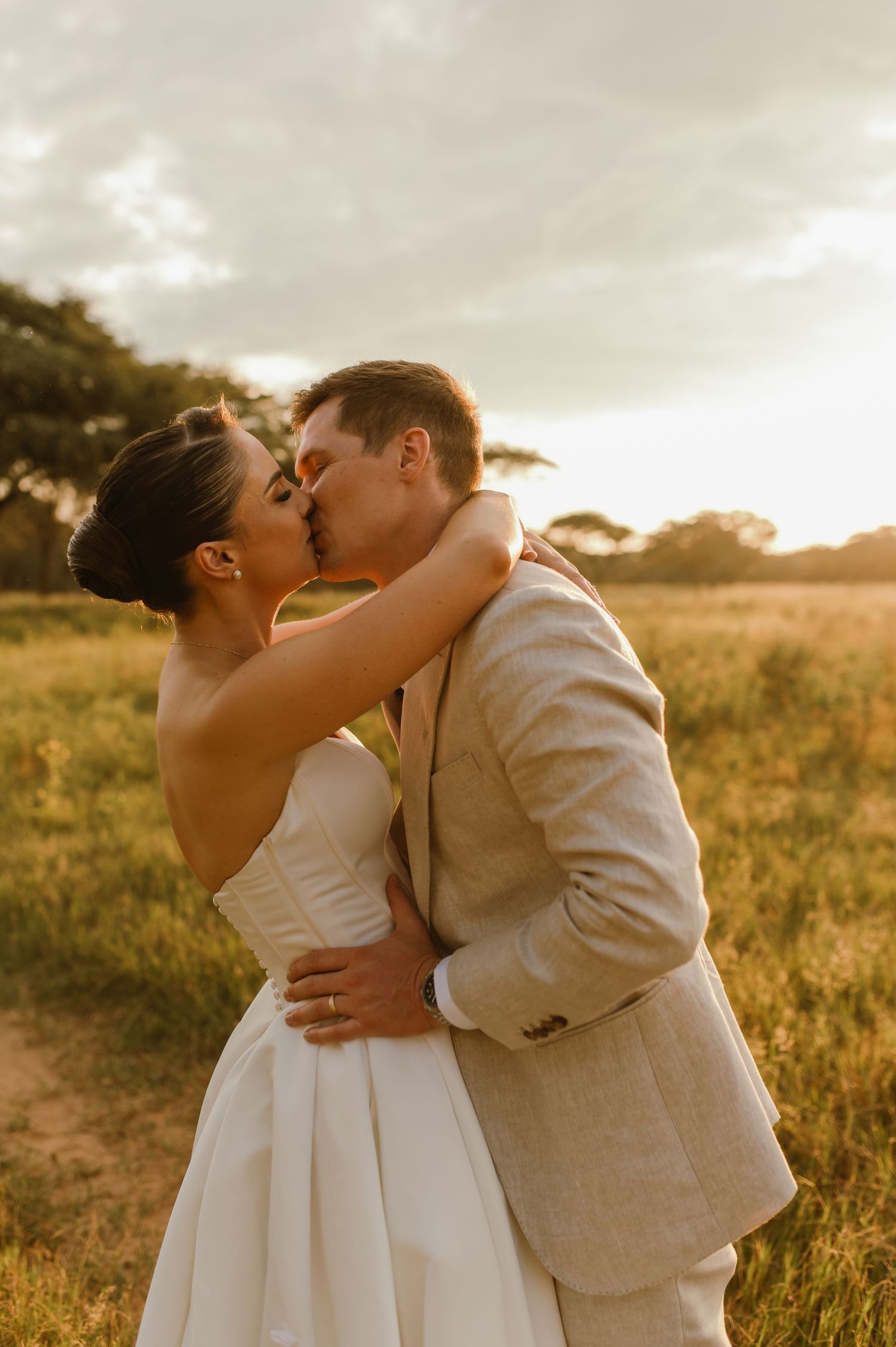 Newlyweds share passionate kisses in a series of sunset photos taken in a rustic outdoor setting.