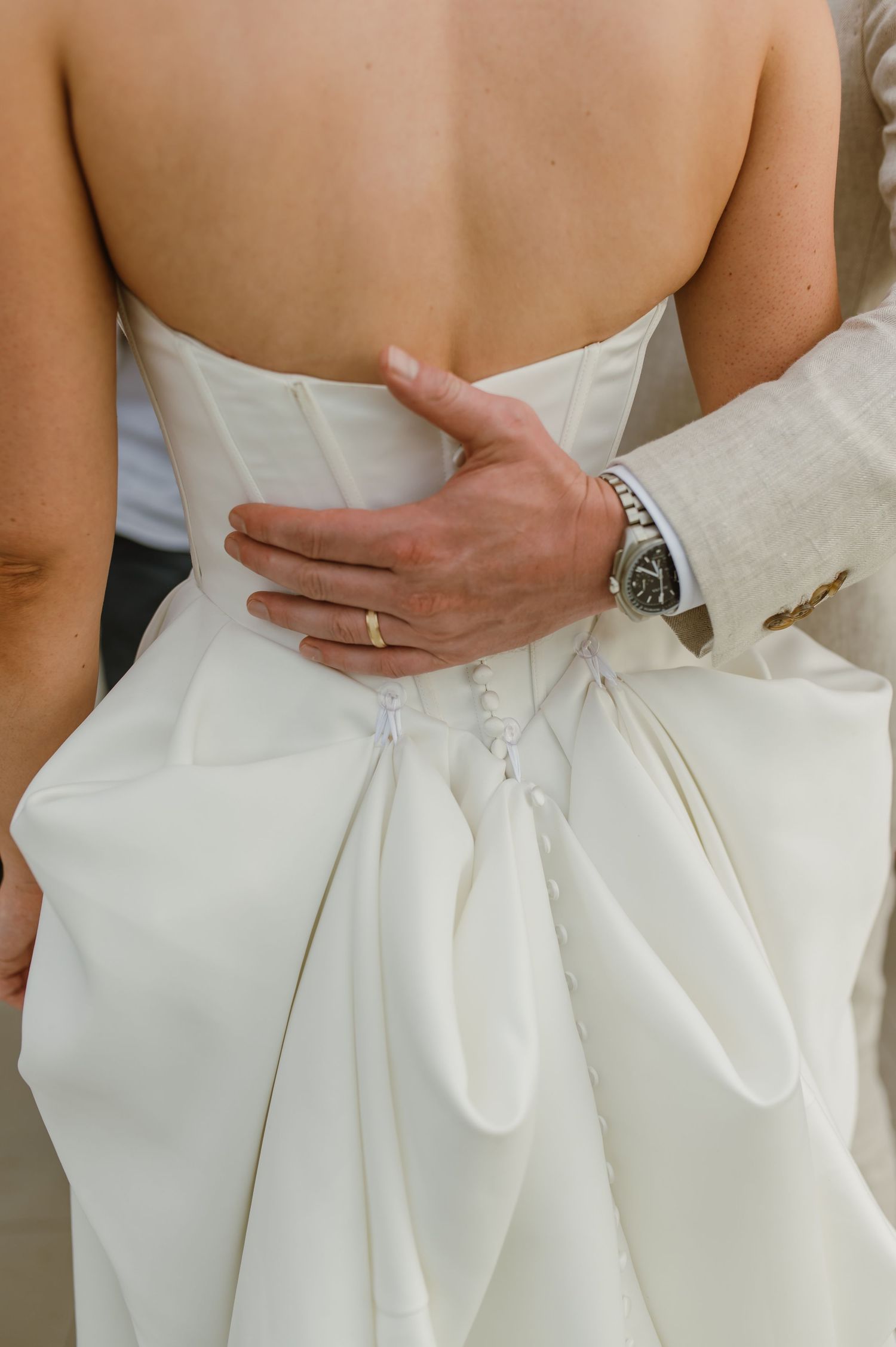 Close-up details of a white wedding dress showing elegant pleating and draping on the back.