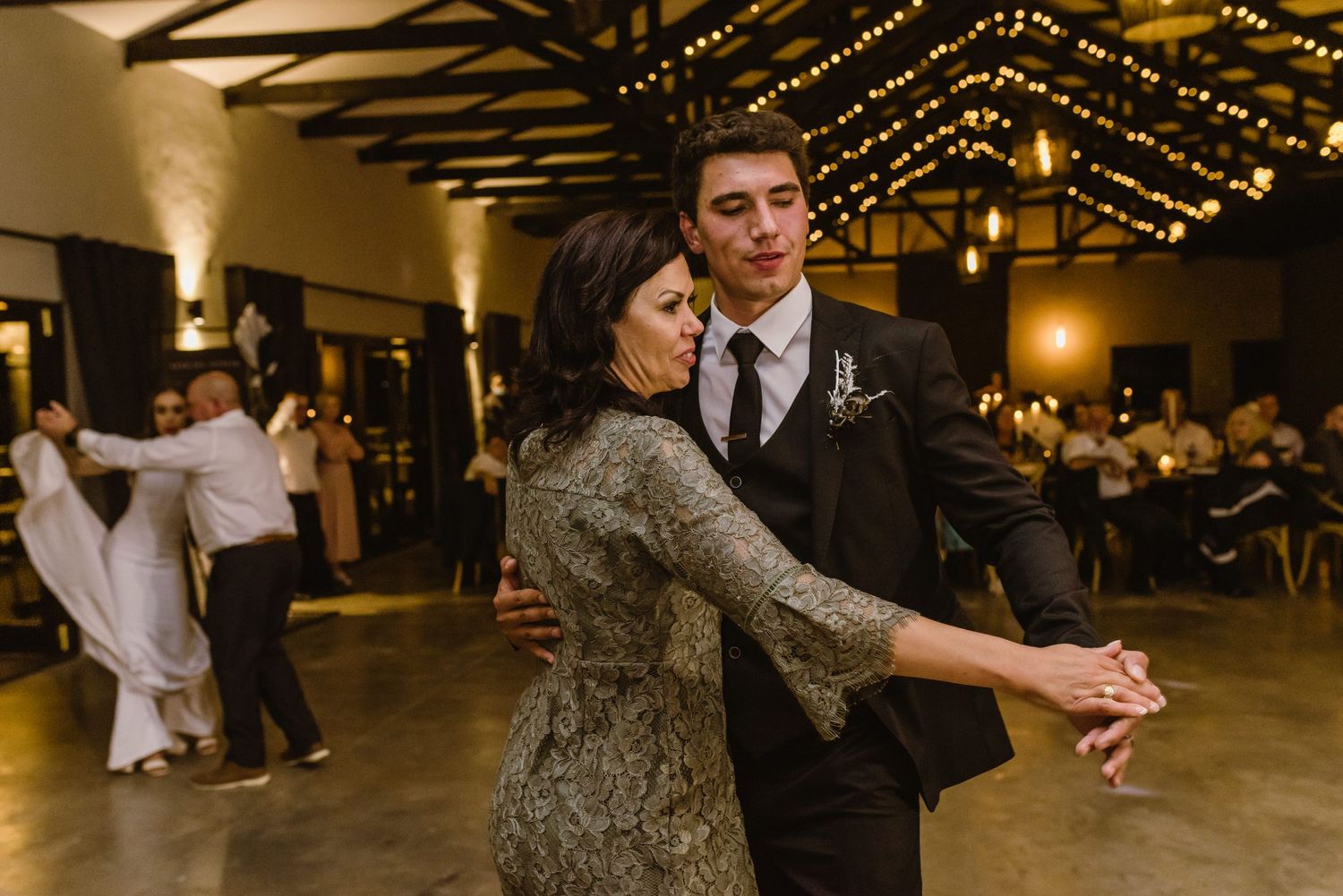 Couples dance together at an evening wedding reception under warm lighting.