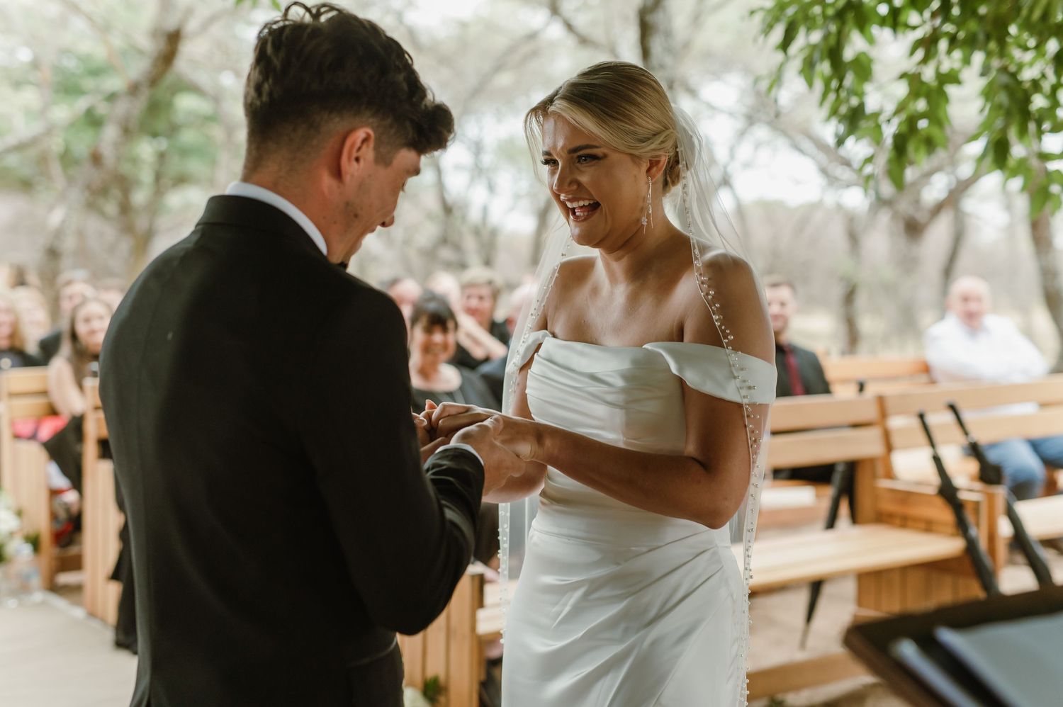 Natural light filters through trees during intimate outdoor wedding ceremony moment.