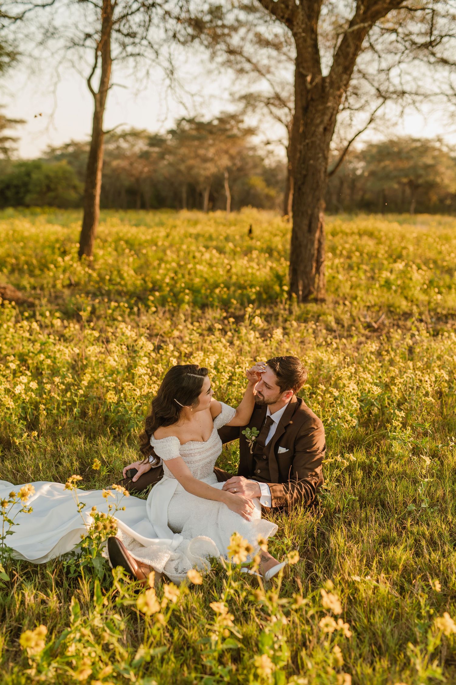 A couple shares an intimate moment on a picnic blanket surrounded by wildflowers at sunset.