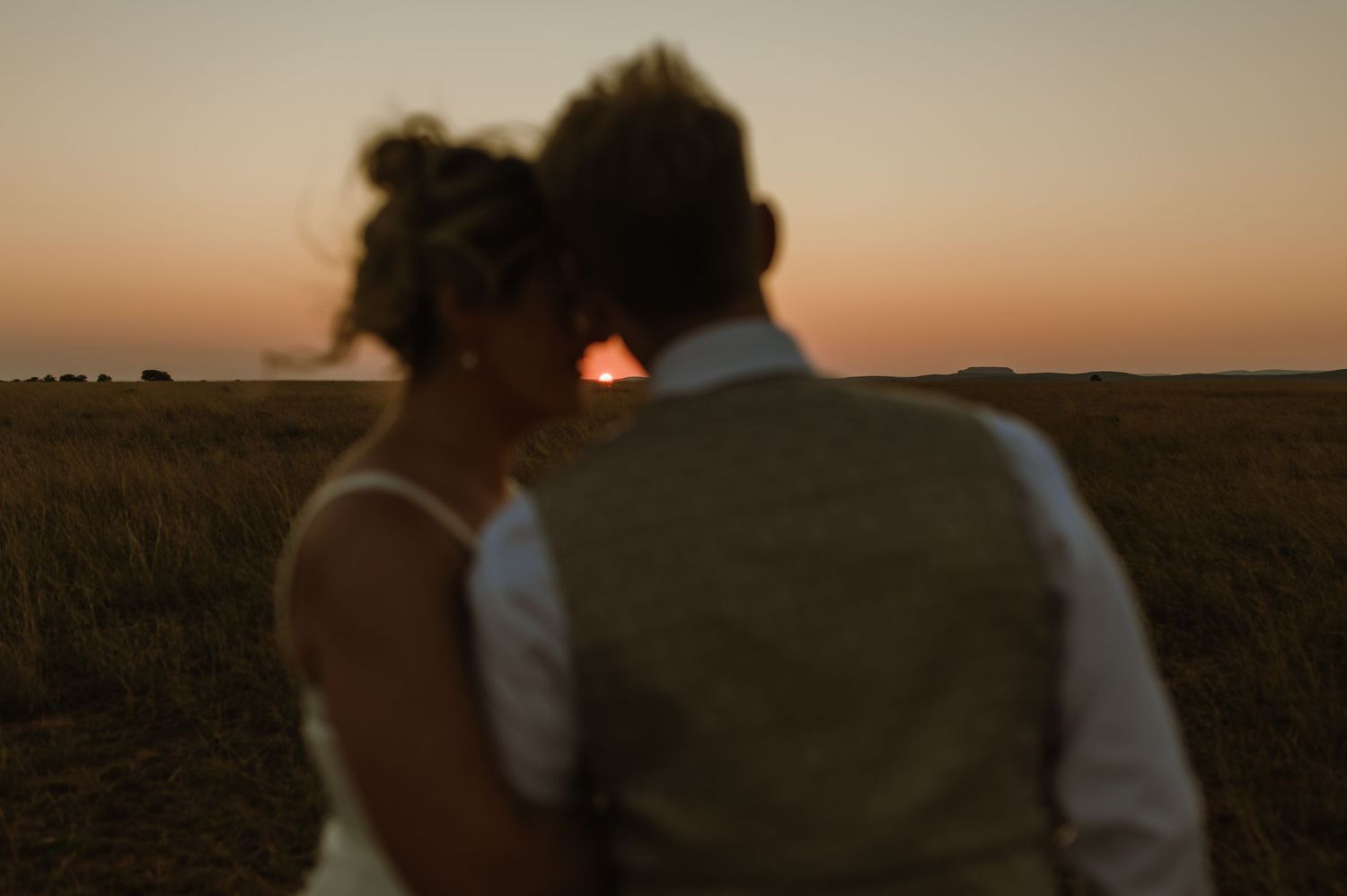 Silhouette of a couple against a warm sunset sky.