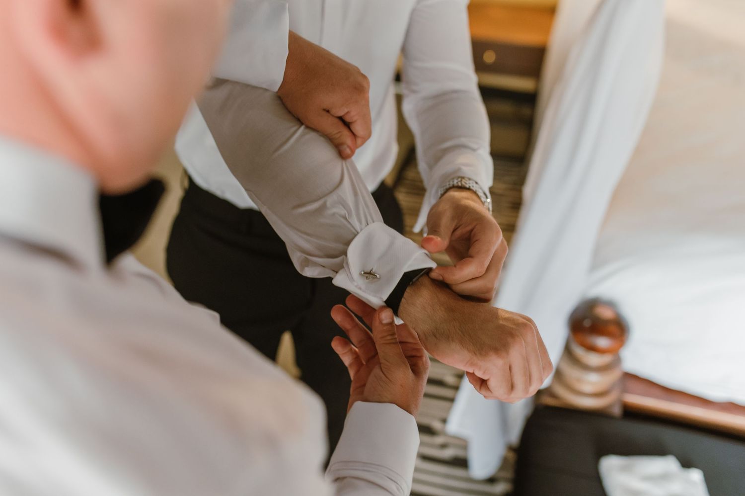 Close-up of hands adjusting formal white dress shirt cuffs.