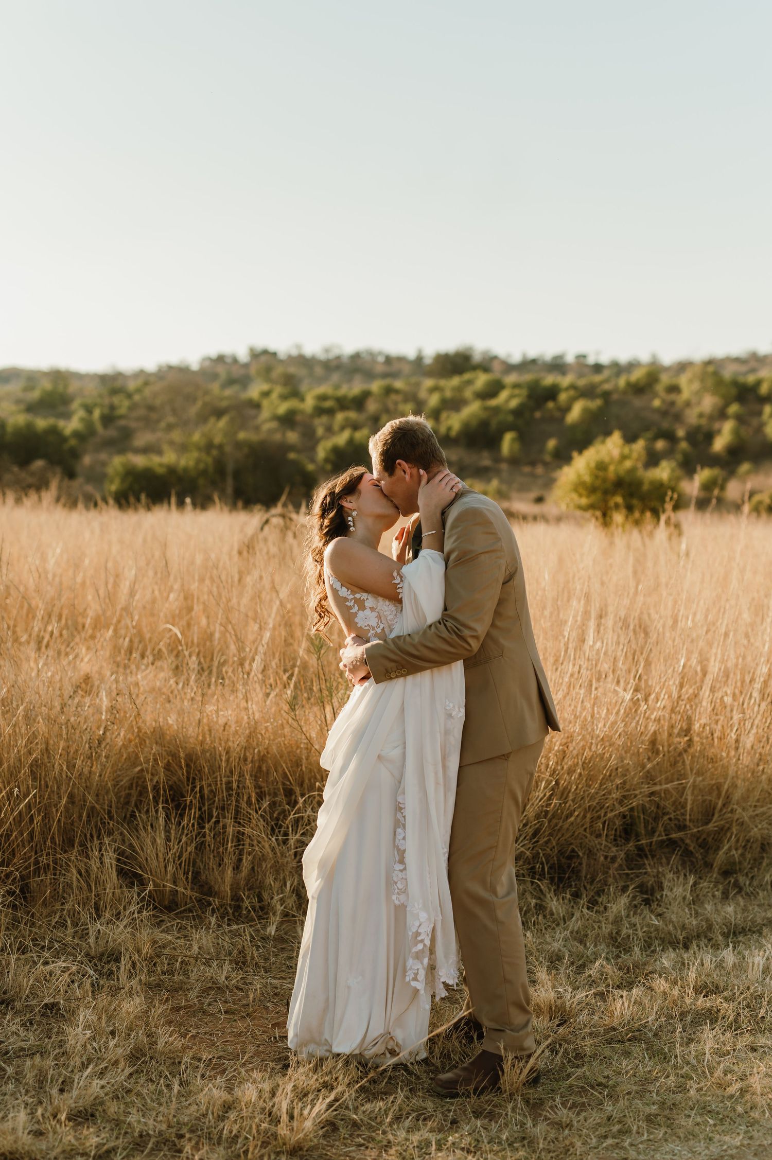 Intimate wedding couple portraits in golden hour light among tall grass.