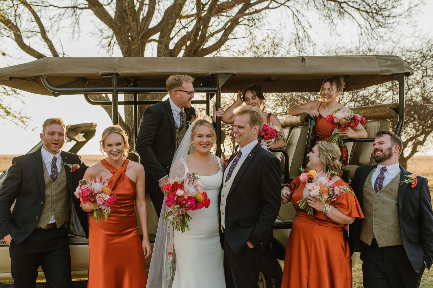 Wedding party celebrates with champagne toasts at an outdoor rustic venue at sunset.