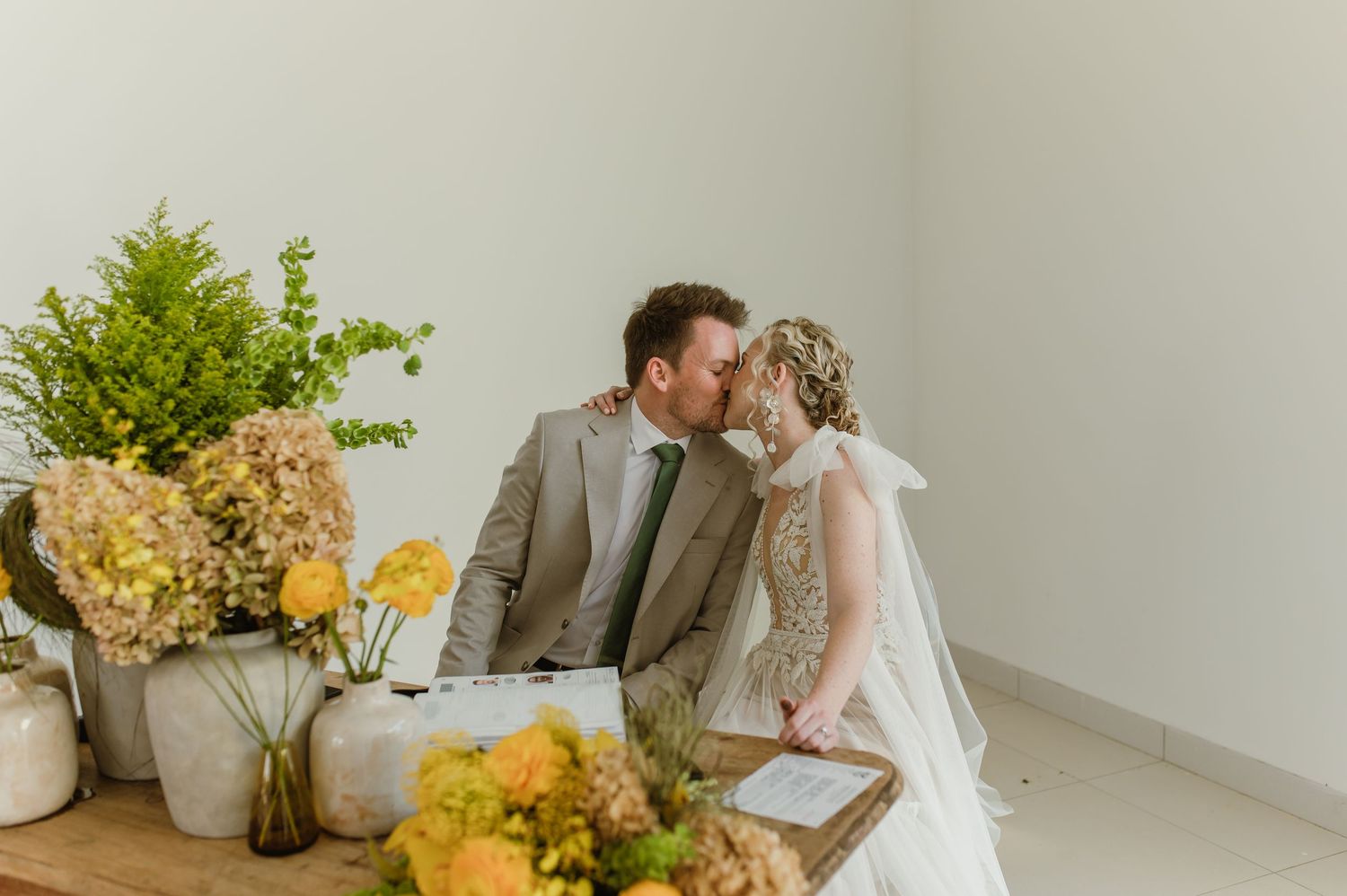 Wedding ceremony preparations with yellow floral arrangements in modern white interior.