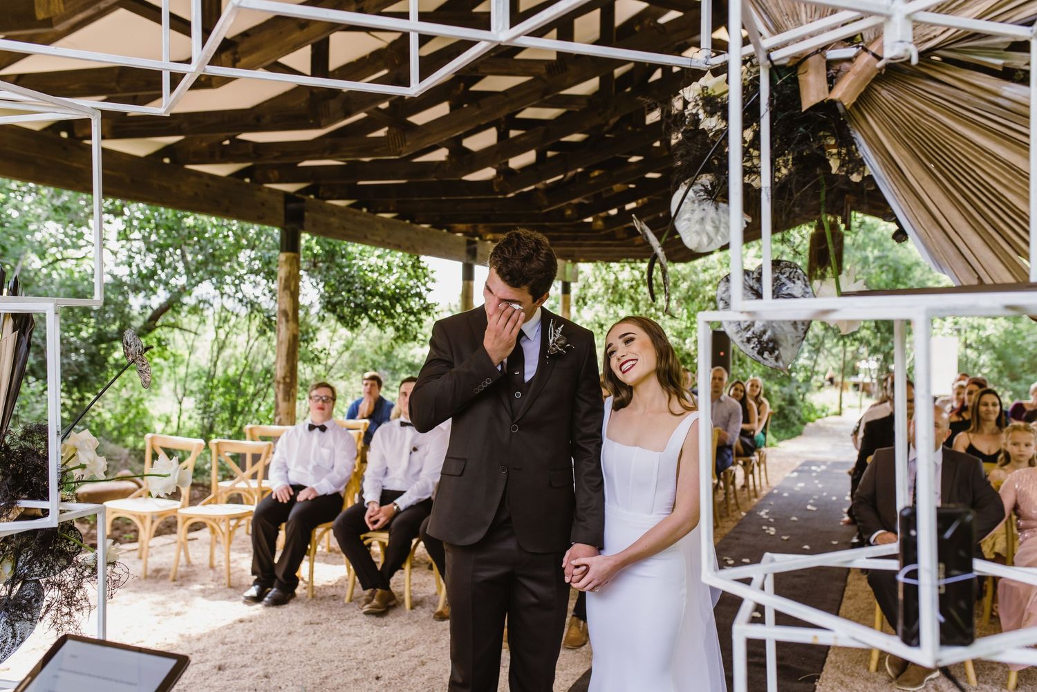 Panoramic view of outdoor wedding venue with white structural elements and wooden beams.