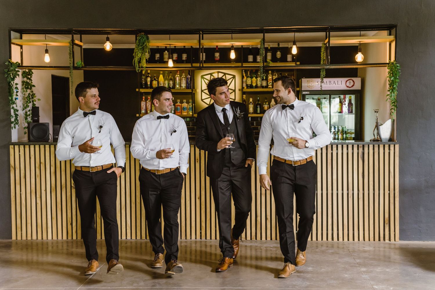 Group poses informally at stylish bar with pendant lighting and wood details.