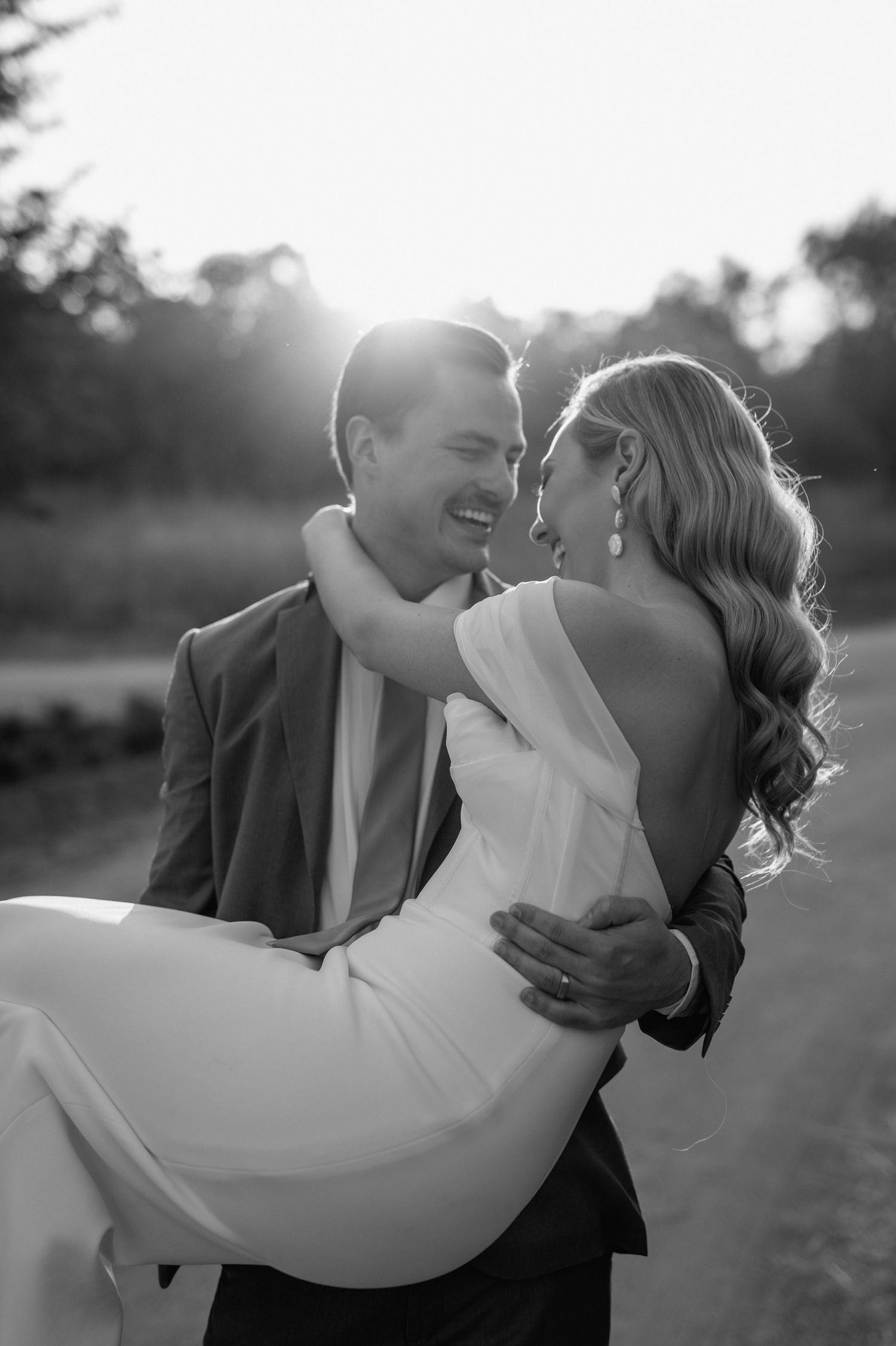 Black and white image captures a romantic dip pose during sunset portraits.